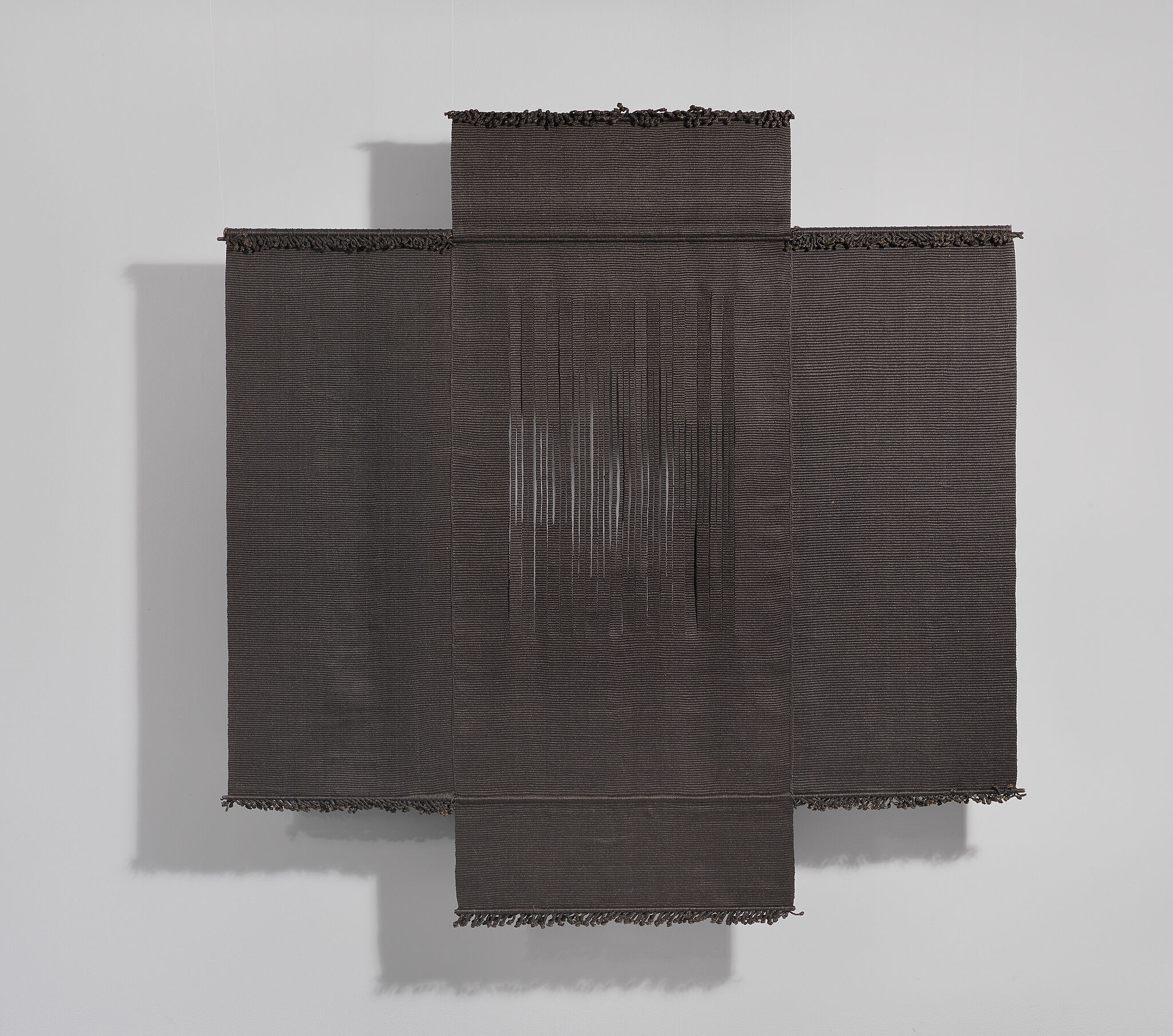 A dark textile hanging on a gallery wall.