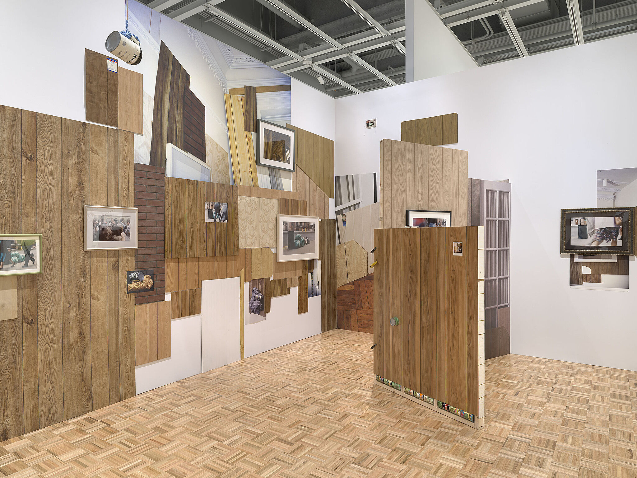 A gallery with fake wood walls, large photographs, and cans of peas.