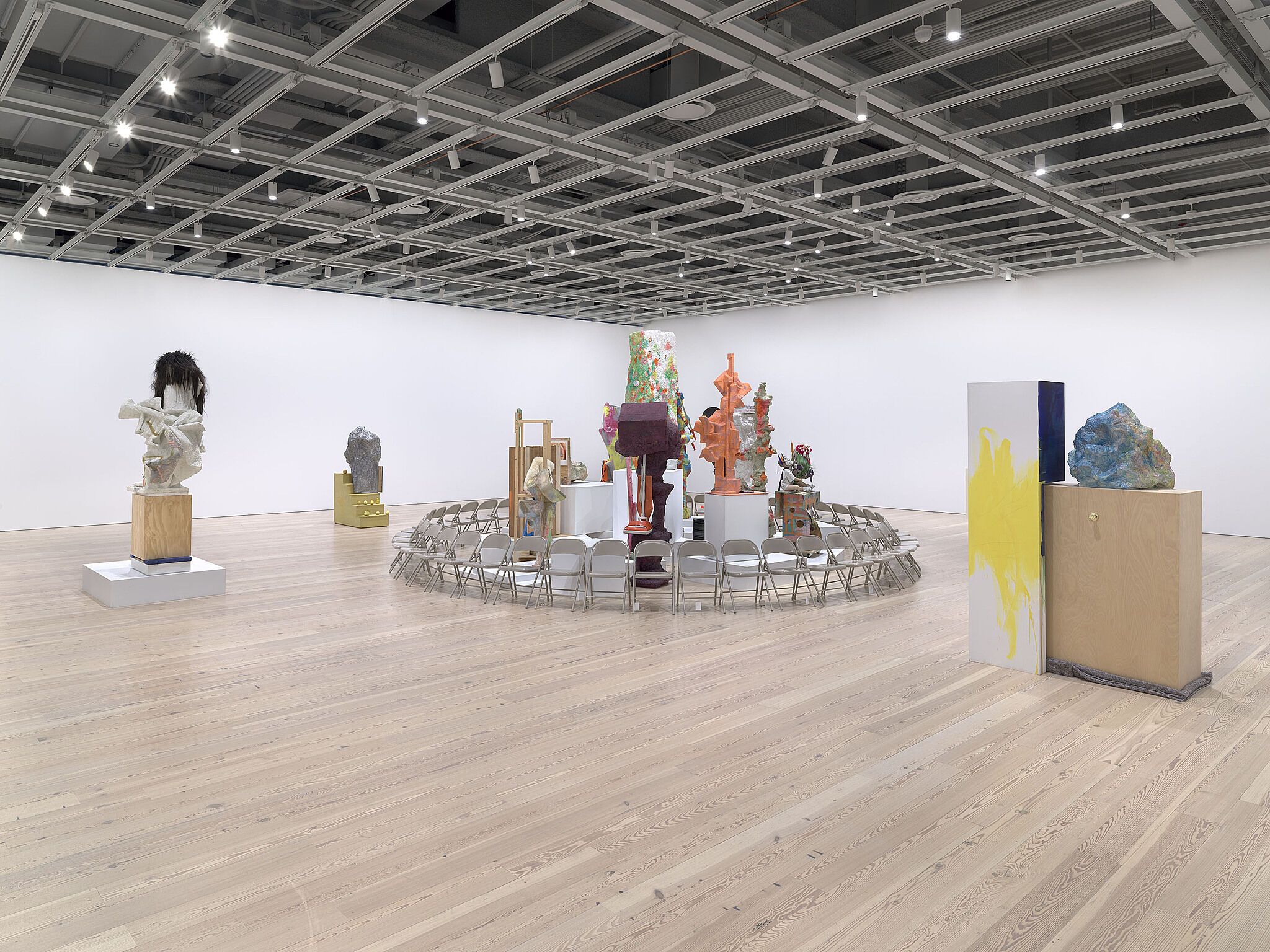 A ring of chairs surround various sculptures in a gallery.