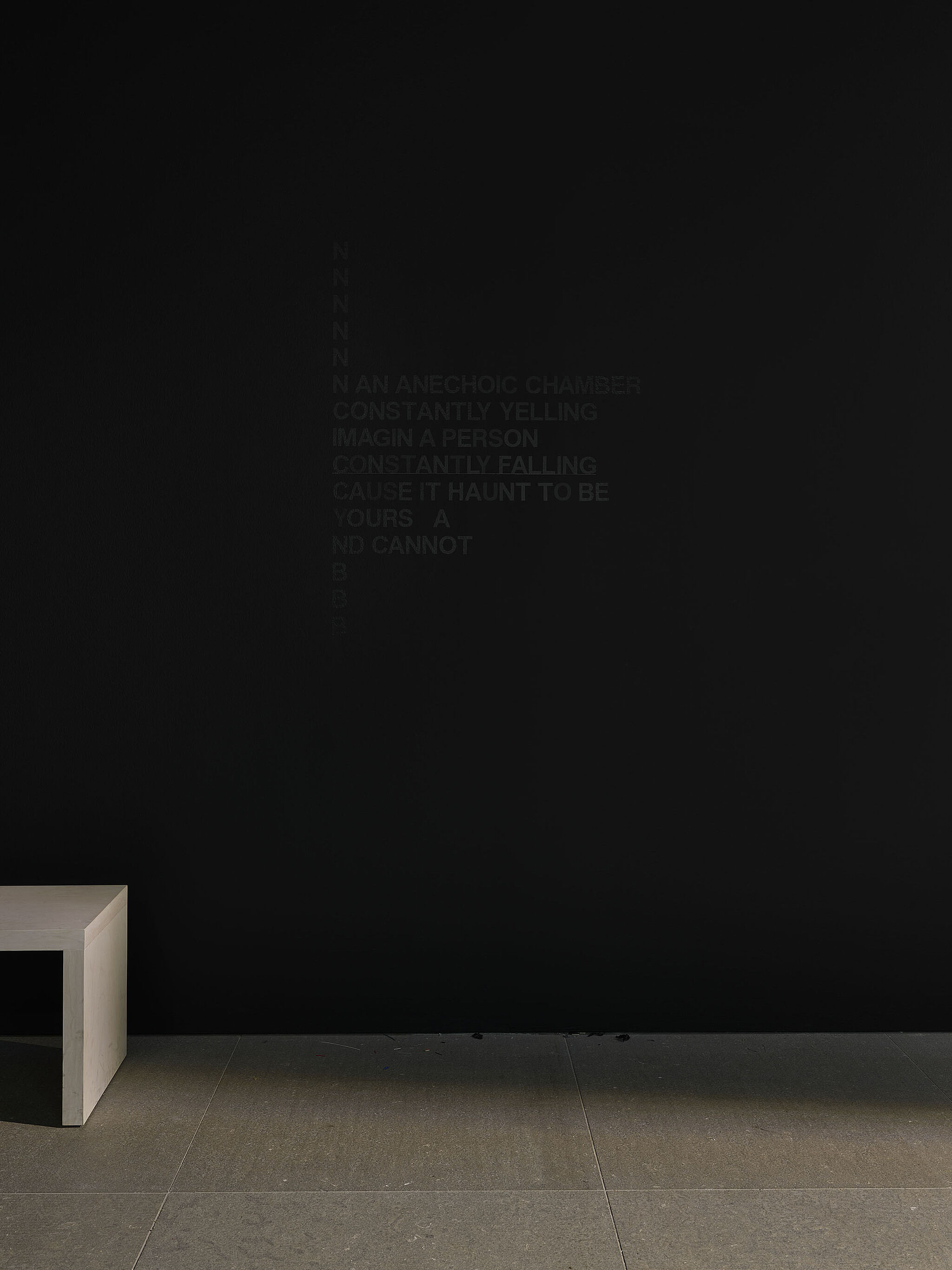 A black wall with black vinyl words.