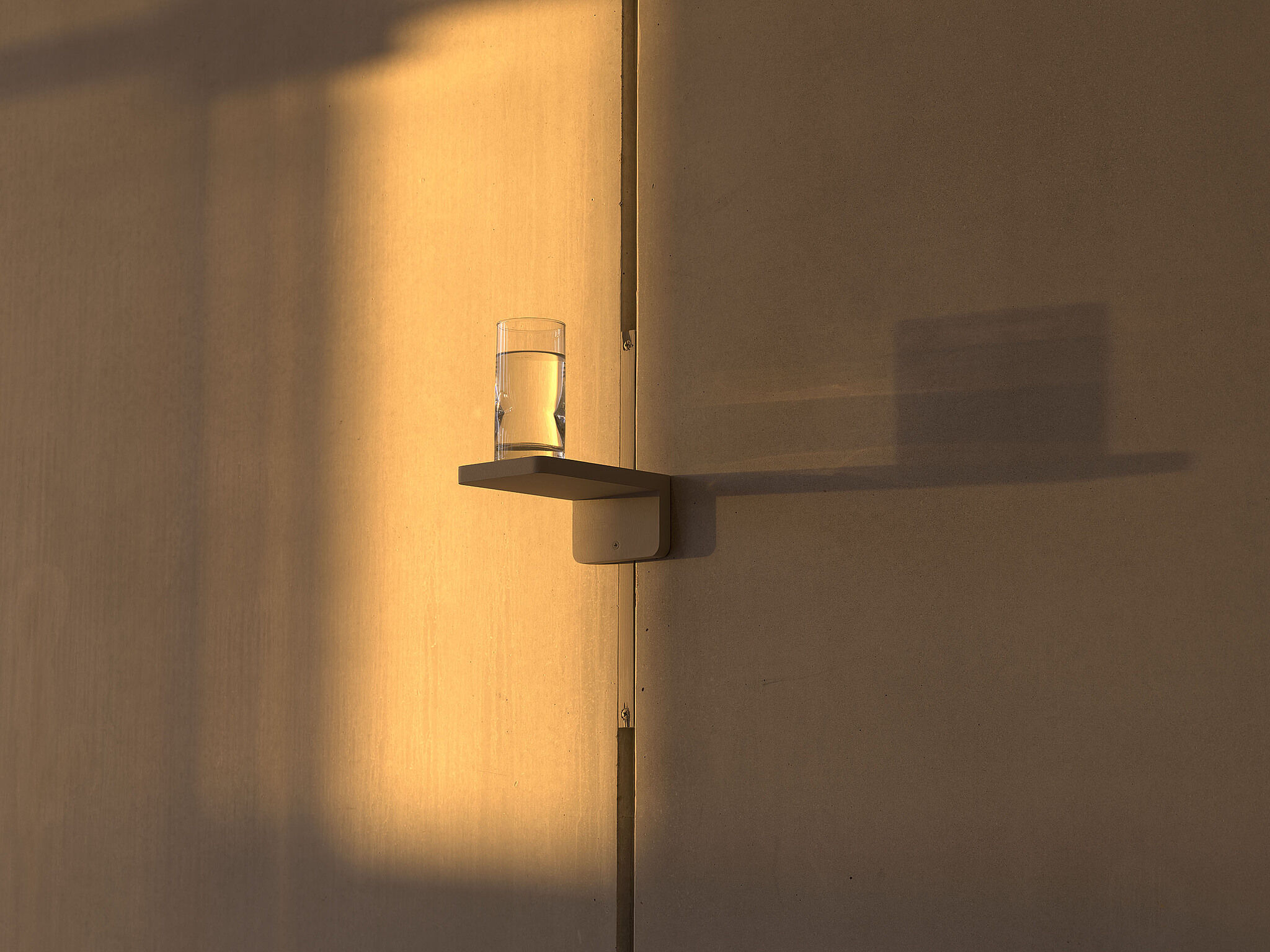 A glass of water sitting on a high shelf in the Whitney lobby.