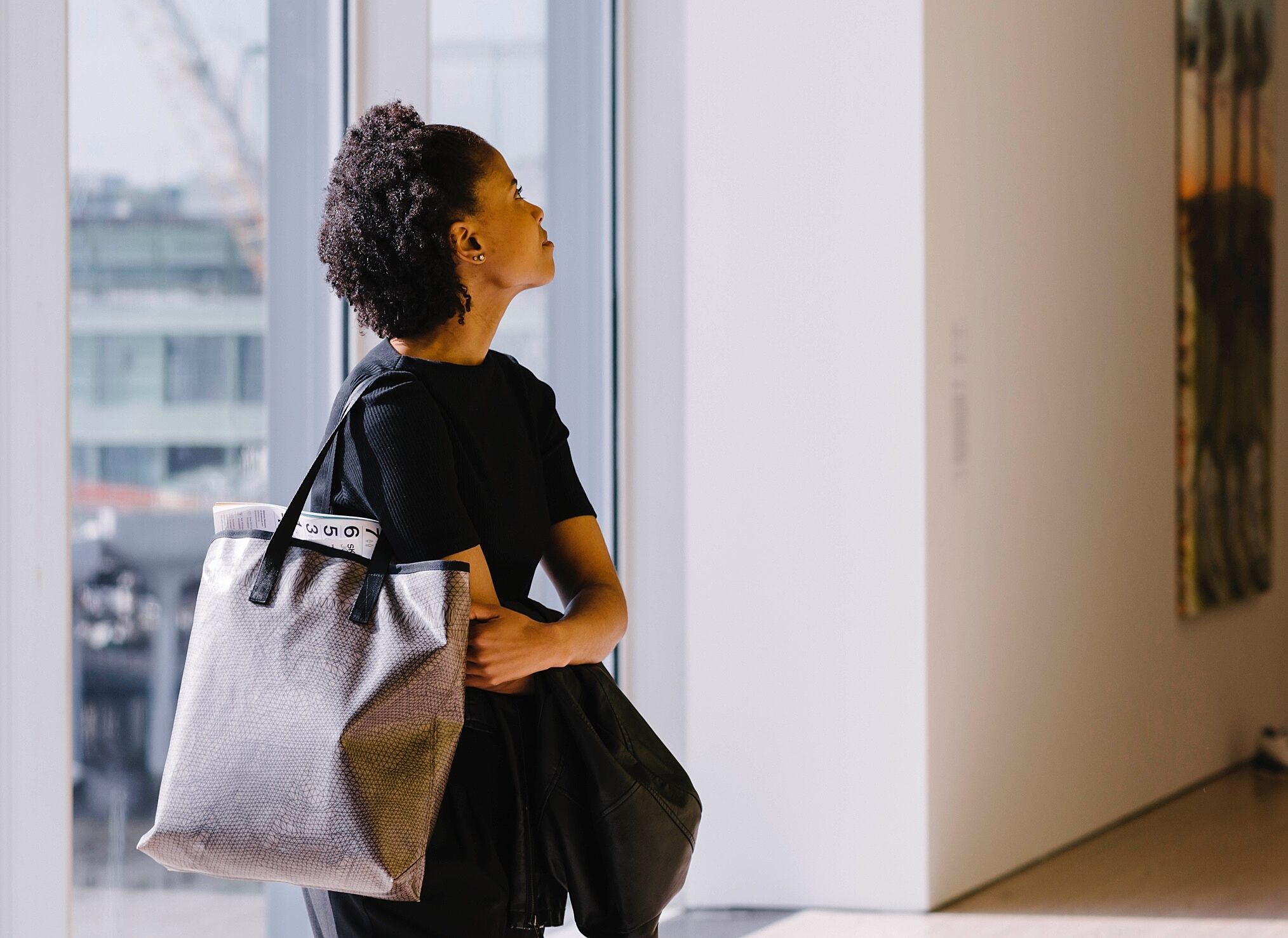 A woman carrying a tote bag looking around at art in the galleries.