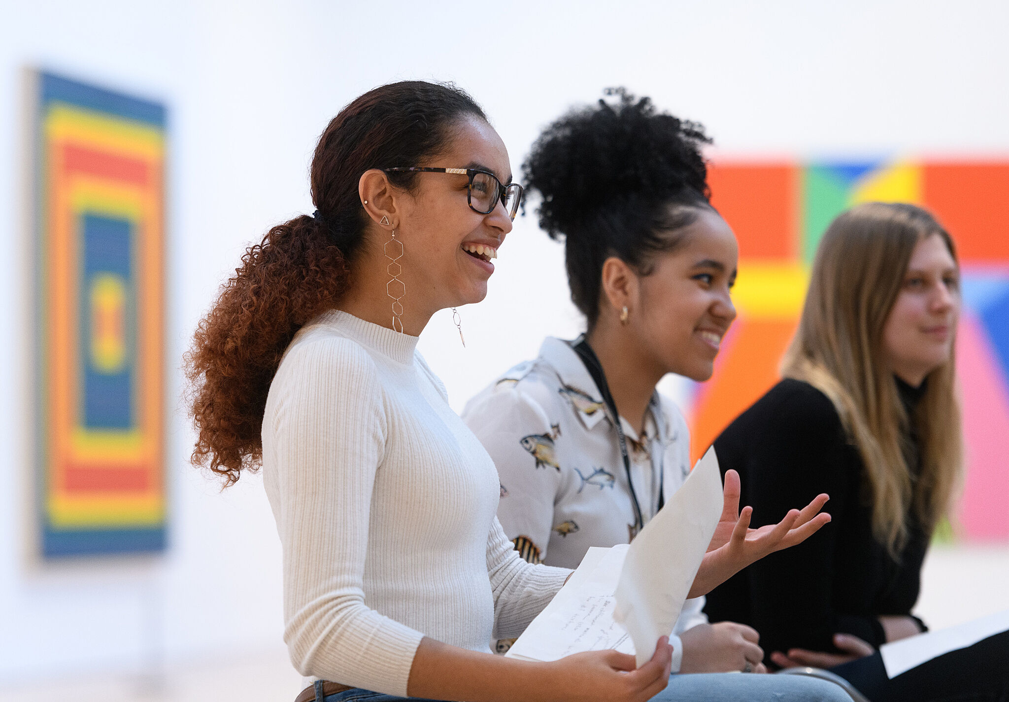 A photo of three teenagers in the Whitney galleries smiling and laughing.