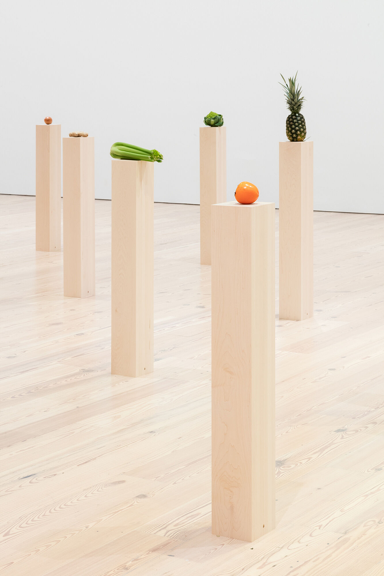 A photo of assorted vegetables and fruits on plinths.
