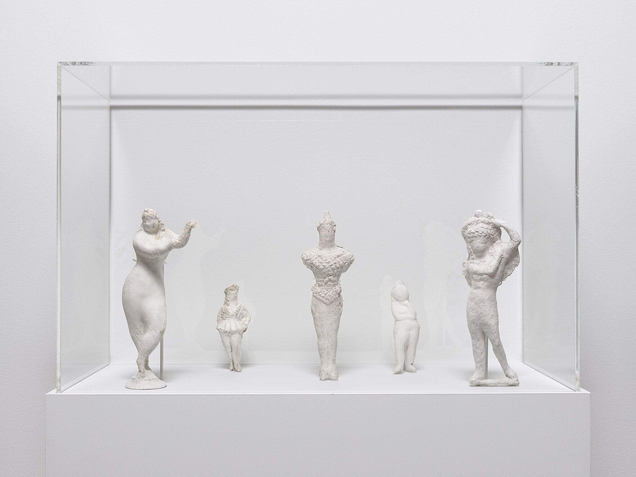 Five small white sculptures of figures.