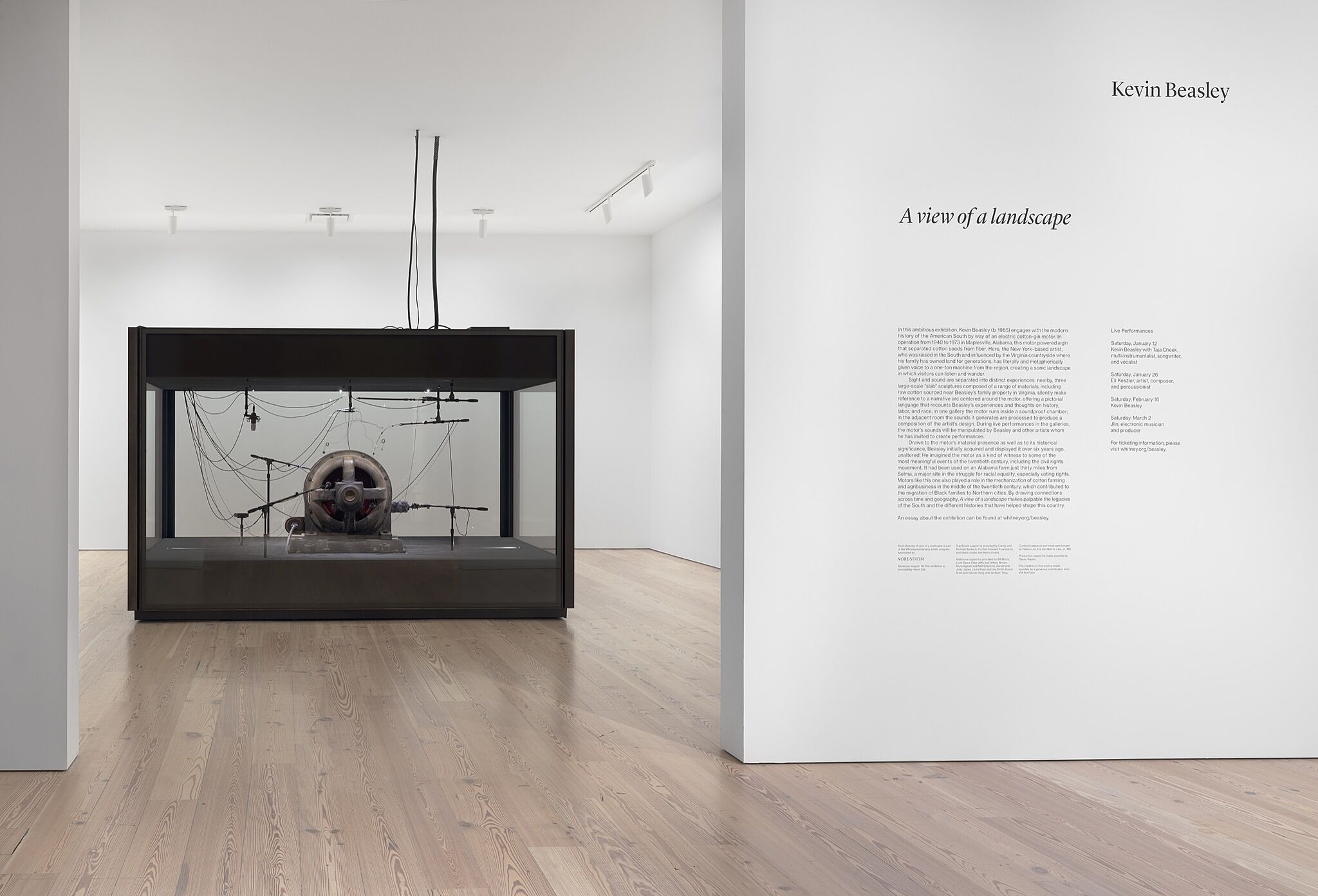 A motor in a glass case sits in a gallery with wall text.