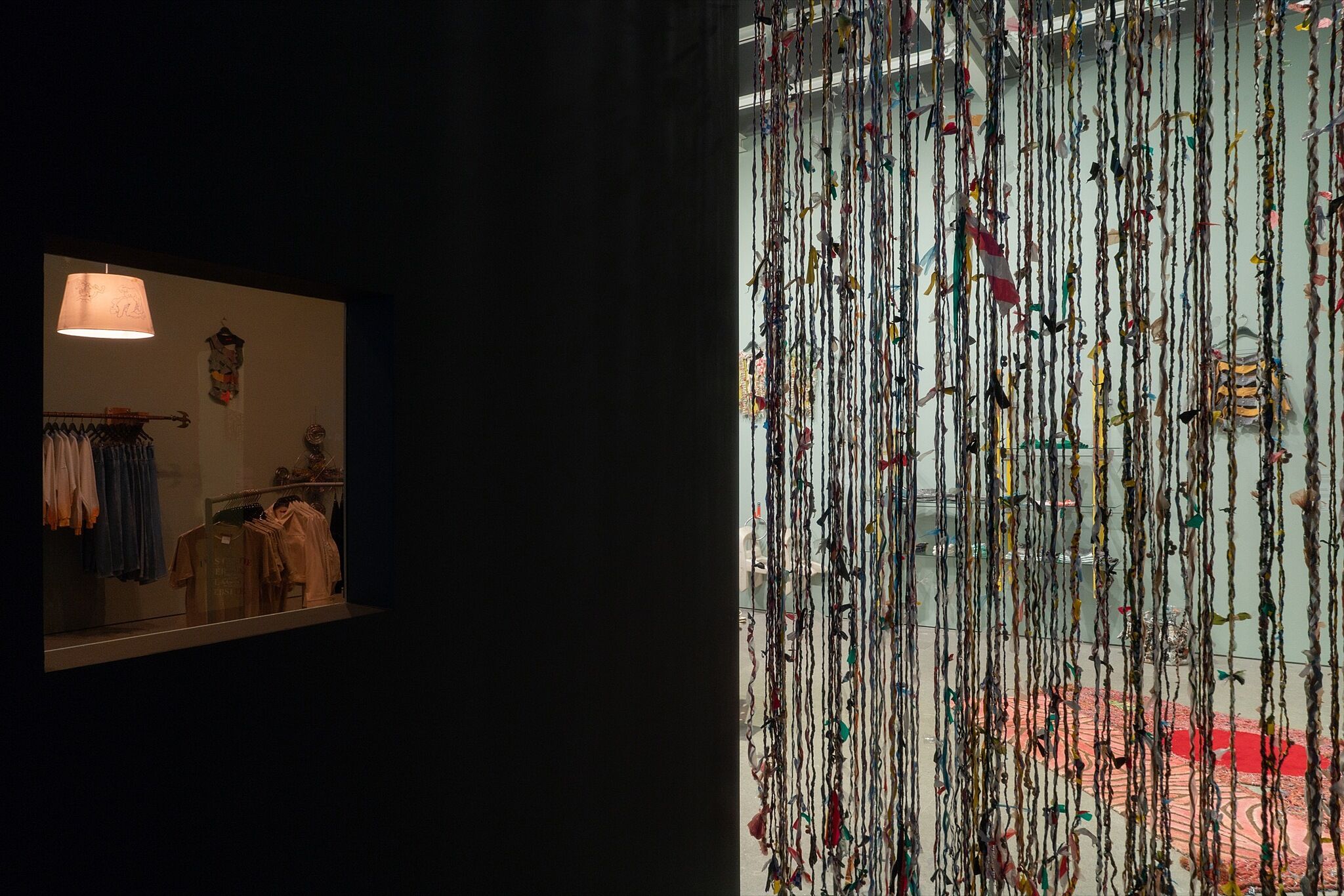 A dimly lit gallery space made to look like a dressing room with a beaded curtain.
