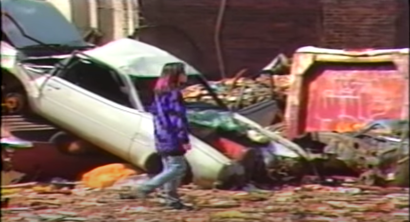 A woman walks through a trash-filled street.