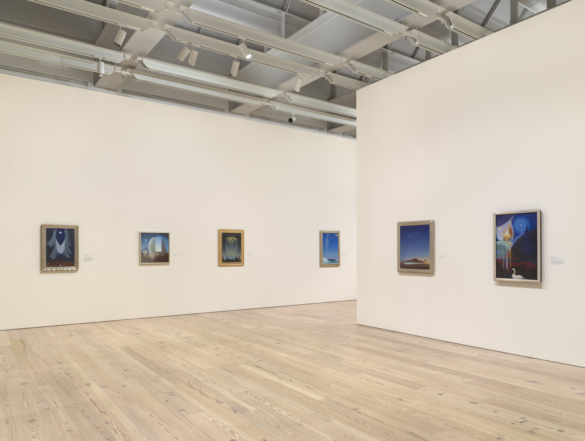 Two white walls appear in the photo of Agnes Pelton: Desert Transcendentalist at the Whitney. From left to right the artwork that appears is, The Guide, 1929; Day, 1935; Messengers, 1932; Voyaging, 1931; Return, 1940; Ahmi in Egypt, 1931. 