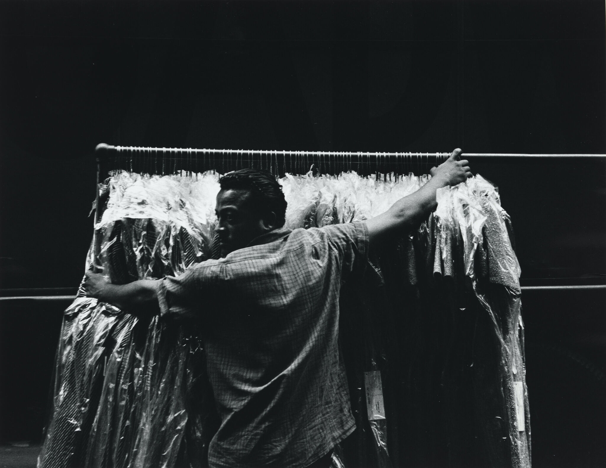 A man standing in front of a rolling rack of garments.