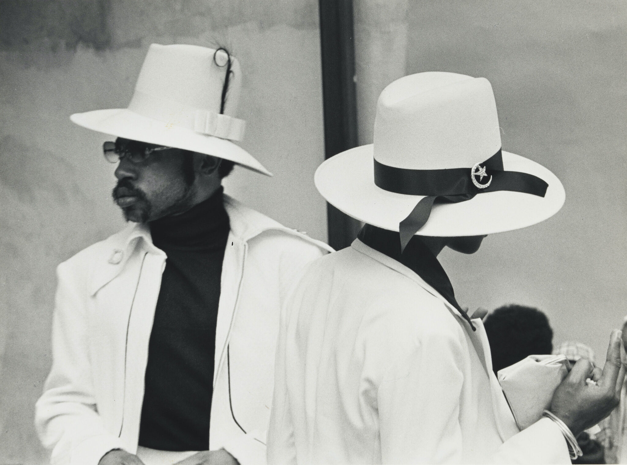 A two people looking opposite ways in white hats.