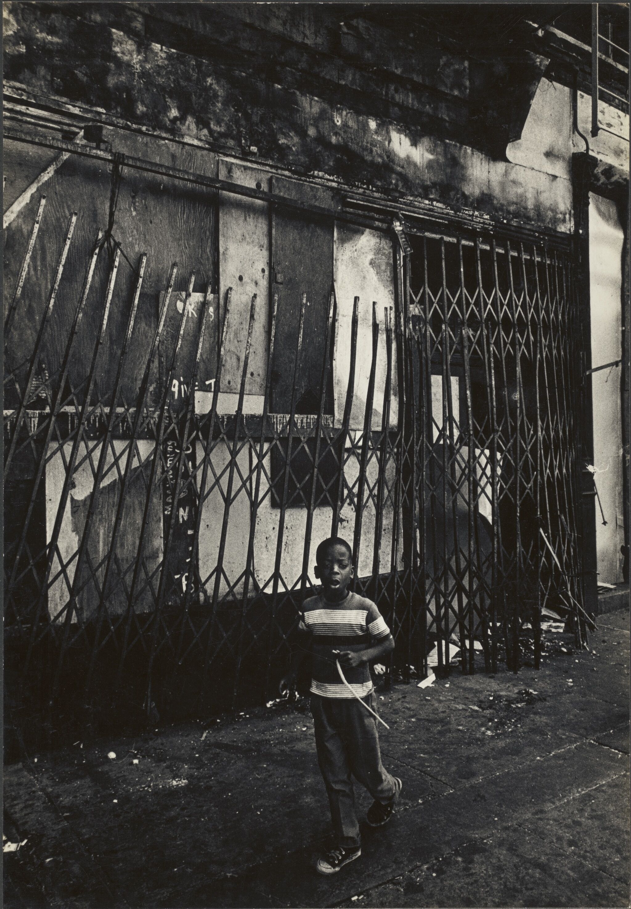 A boy in front of a tall gate.