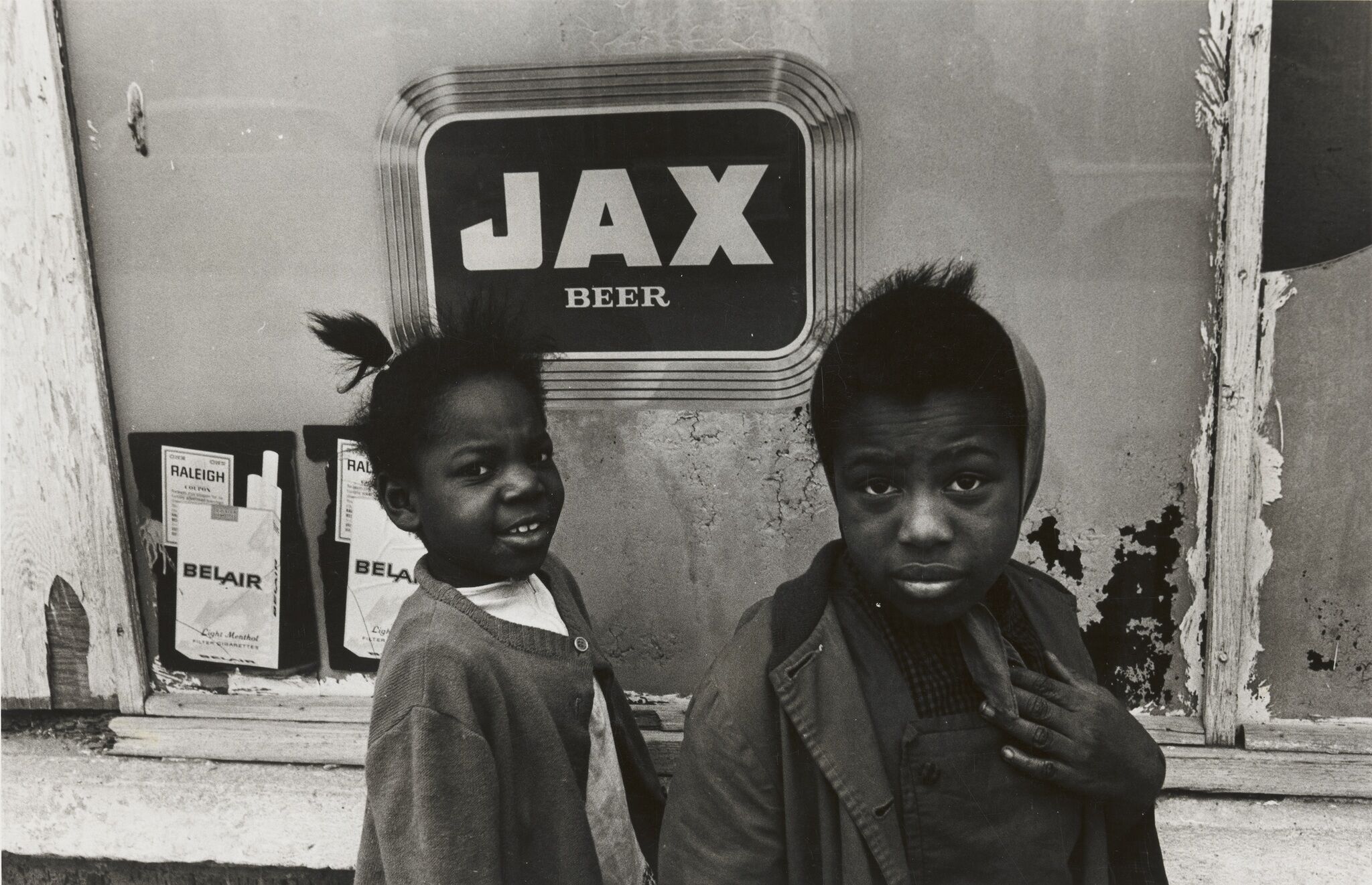 Two children in front of a beer sign.