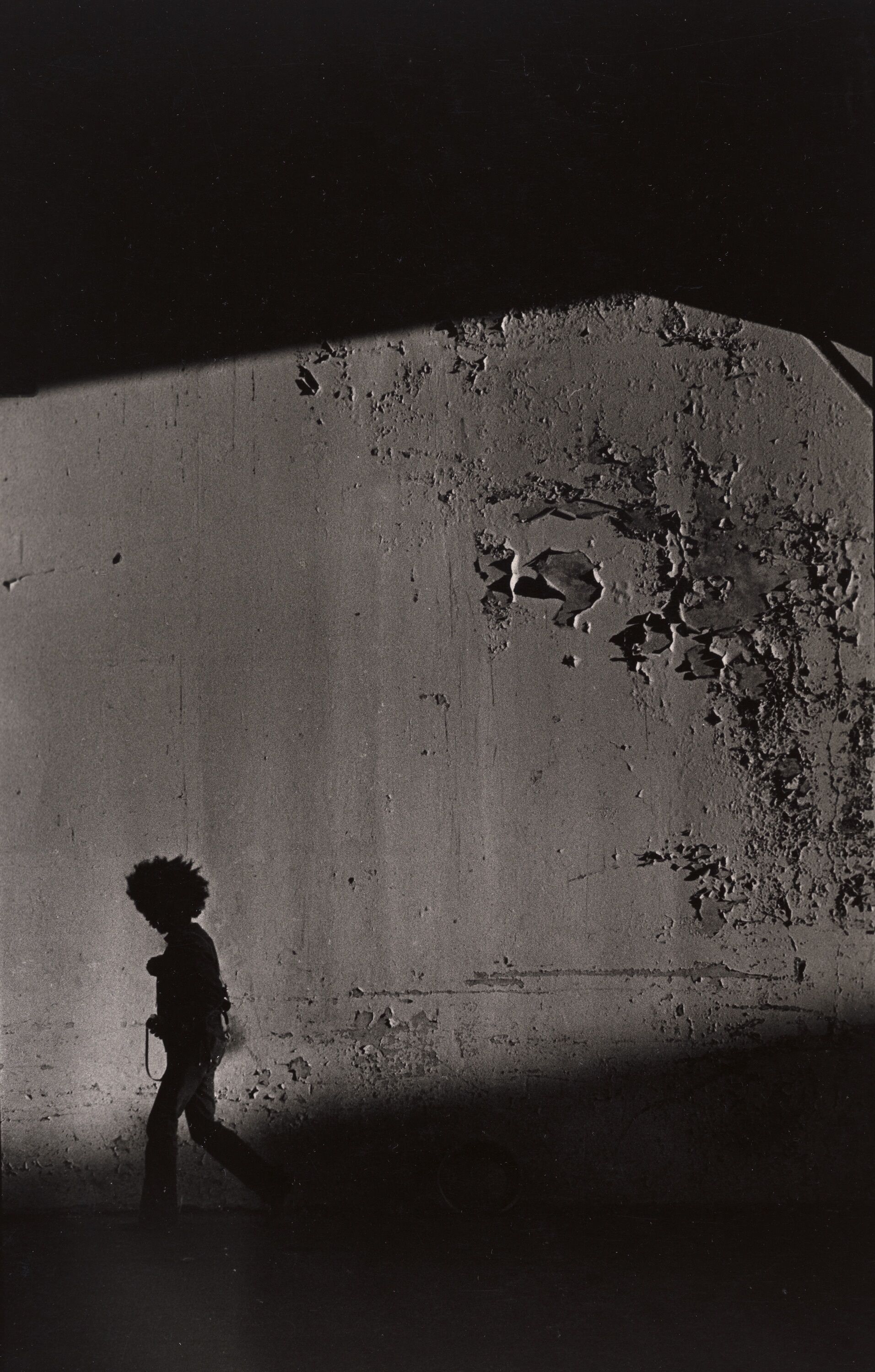 A shadow of a person against a cement wall.