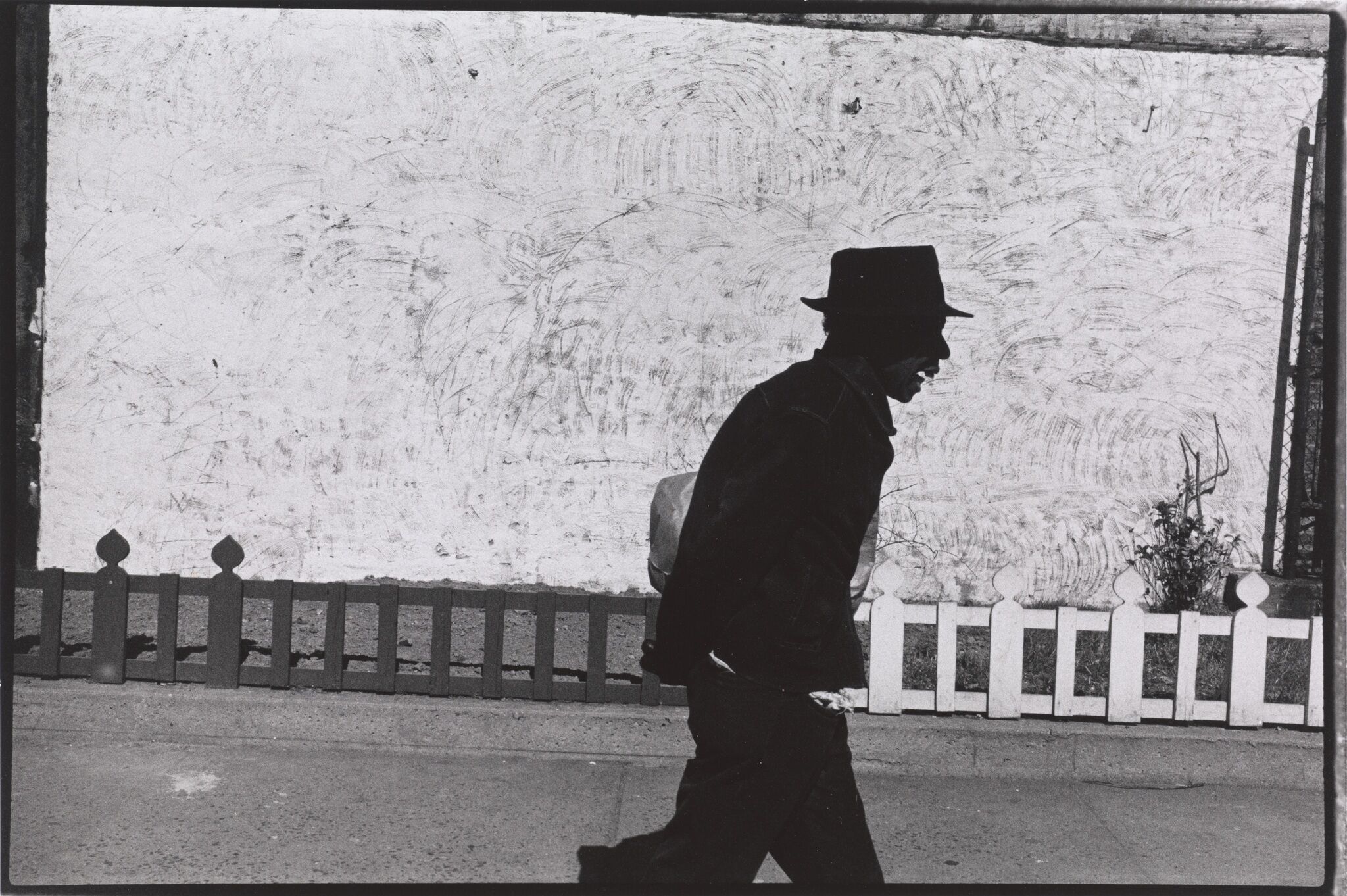 A man wearing a hat walking down a street.