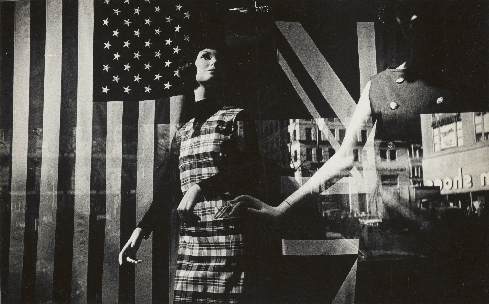 A glass storefront window displaying mannequins in front of an American flag.