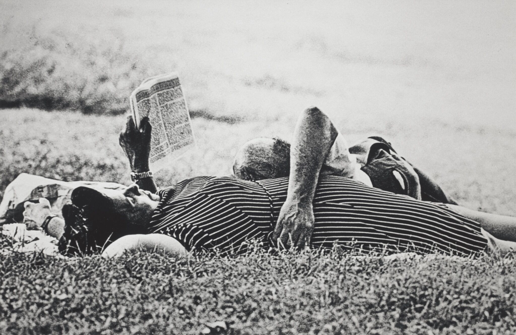 Two people lying down on a field of grass.