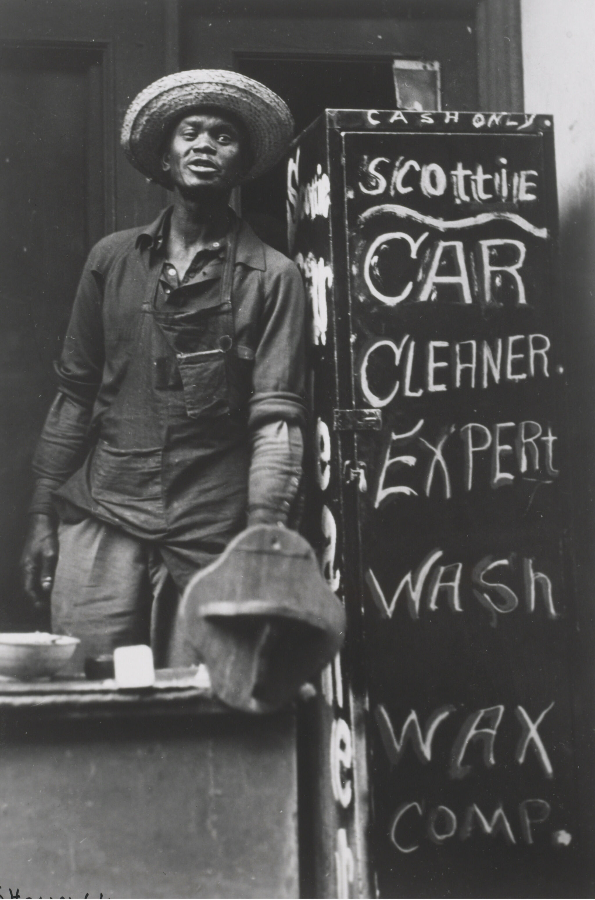 A man in a hat standing next to a cabinet with writing on it. 