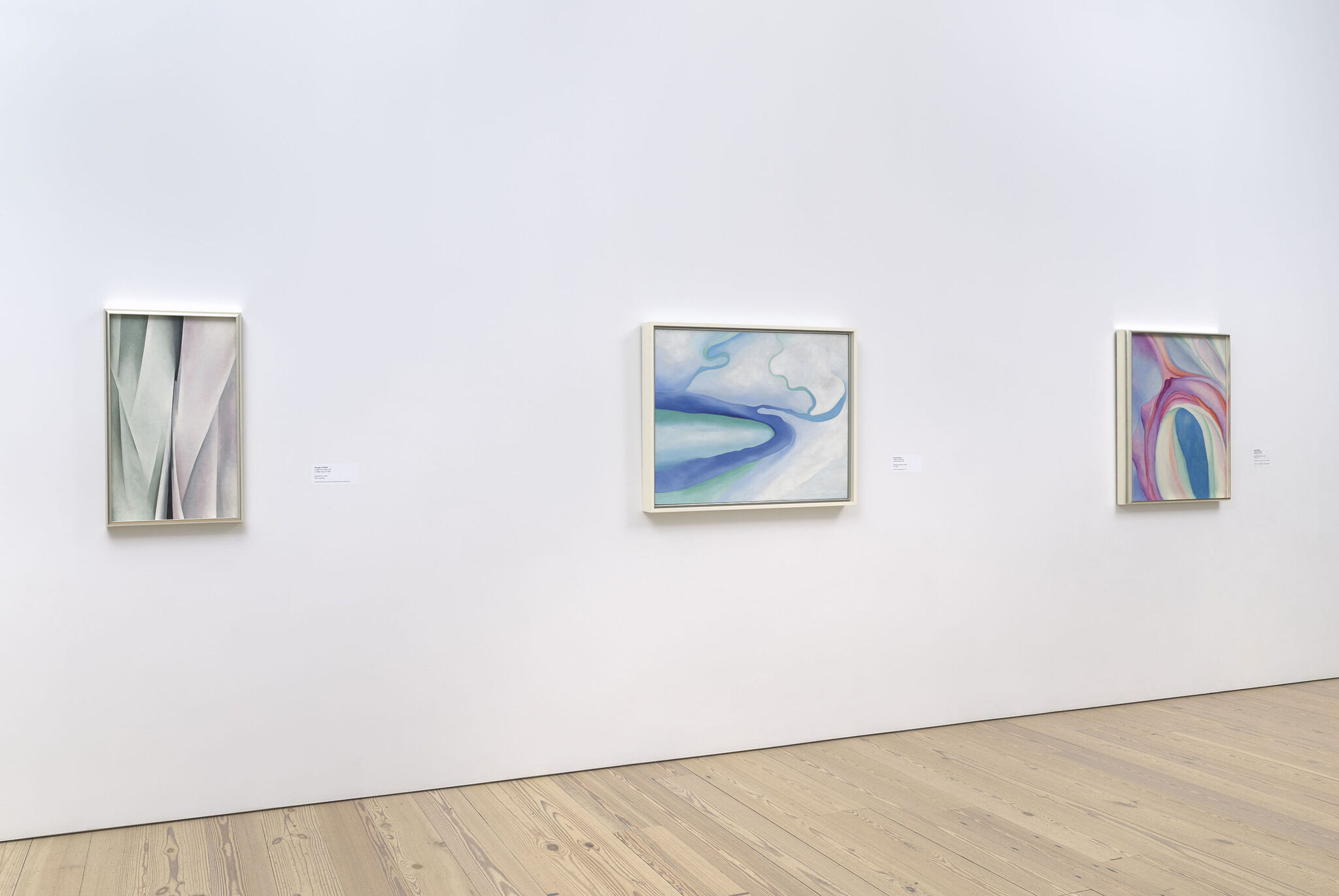 Three works of art displayed on a wall of a gallery.