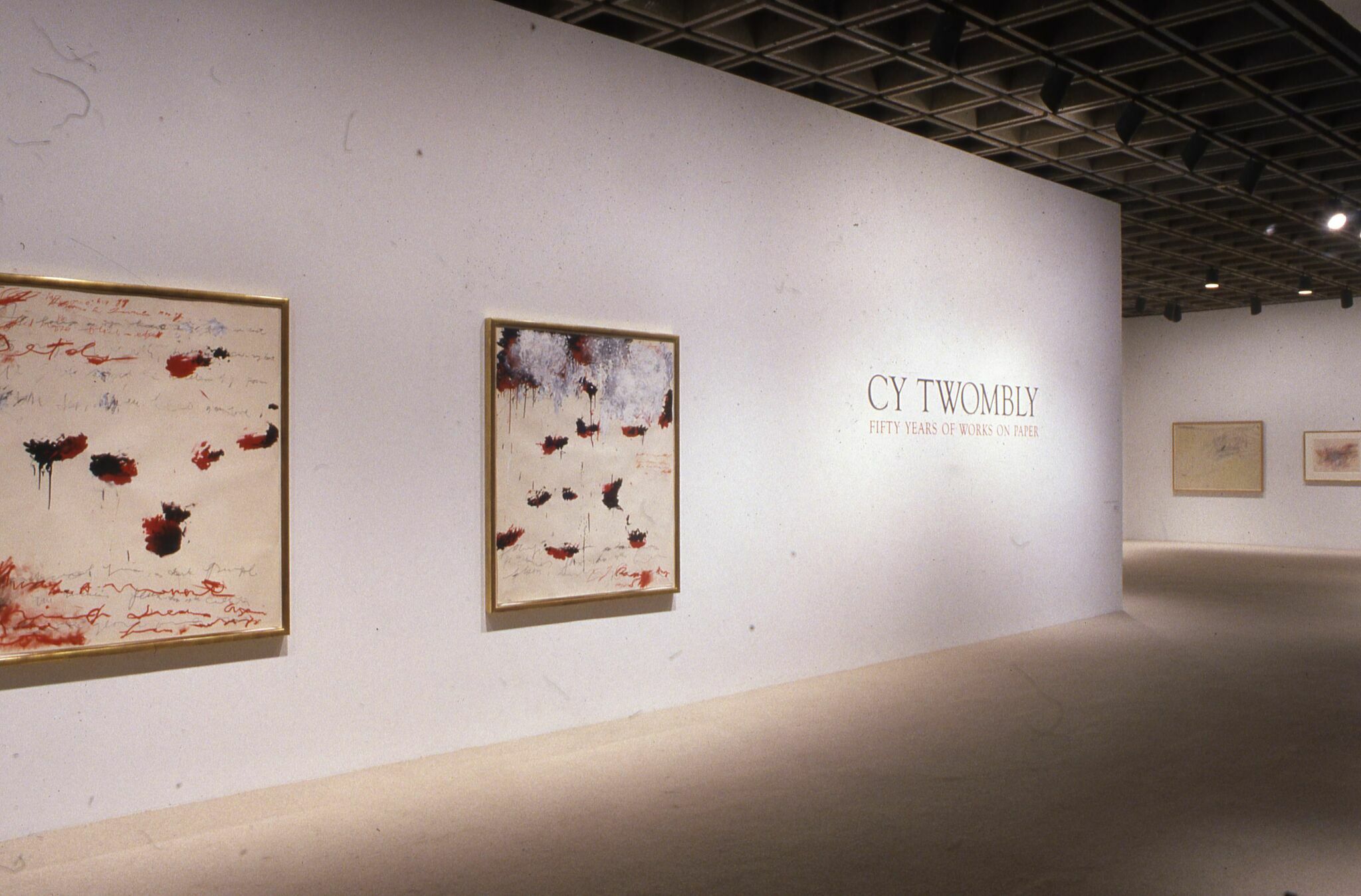 Works of art displayed on a wall alongside wall text for Cy Twombly: Fifty Years of Works on Paper.