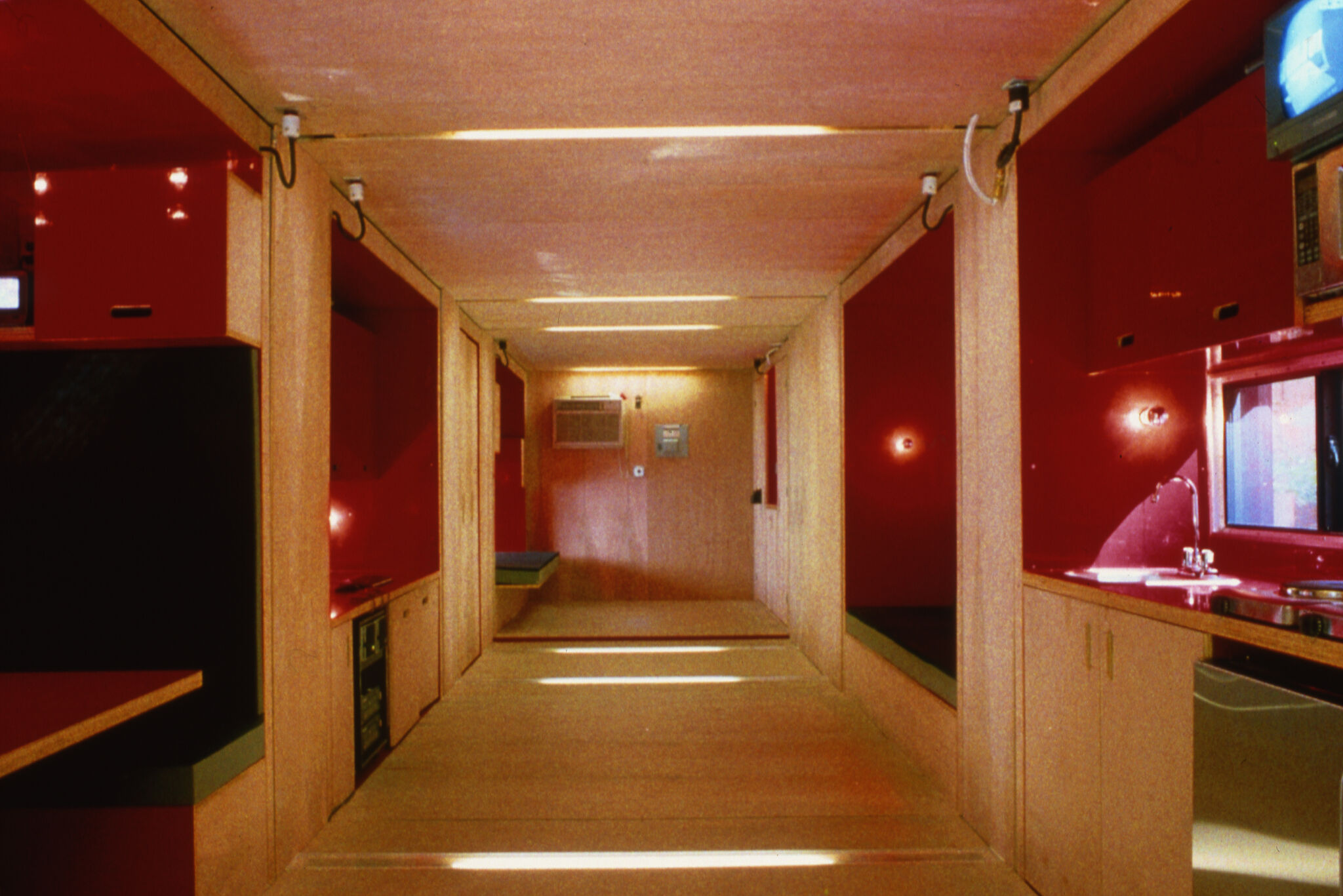 The inside of LOT-EK: Mobile Dwelling Unit, made up of red and wooden interiors.