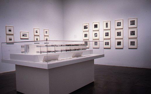 A gallery with photography displayed in frames on the walls and in a glass case.