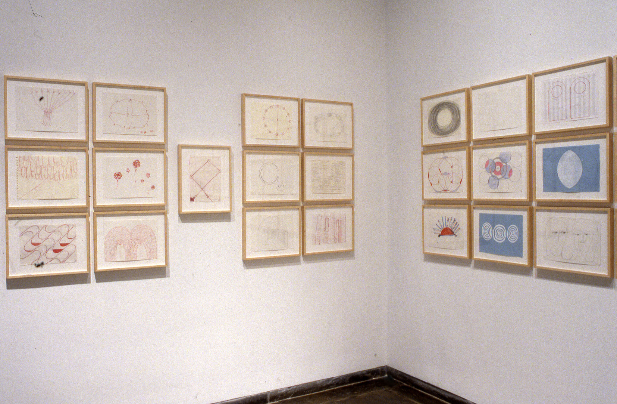 Drawings displayed in frames hung on walls of a gallery.