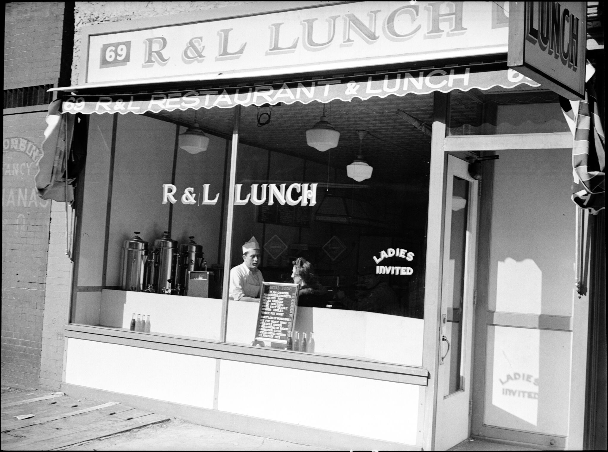 A black-and-white photo of a storefront with large lettering that reads "R & L Lunch". 