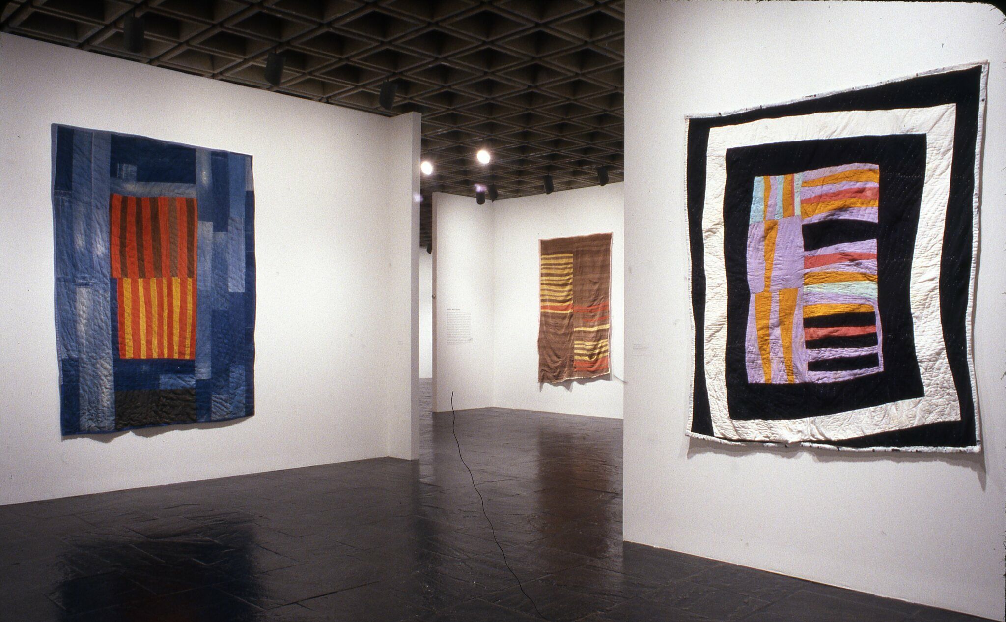 A gallery with colorful quilts displayed on the walls.