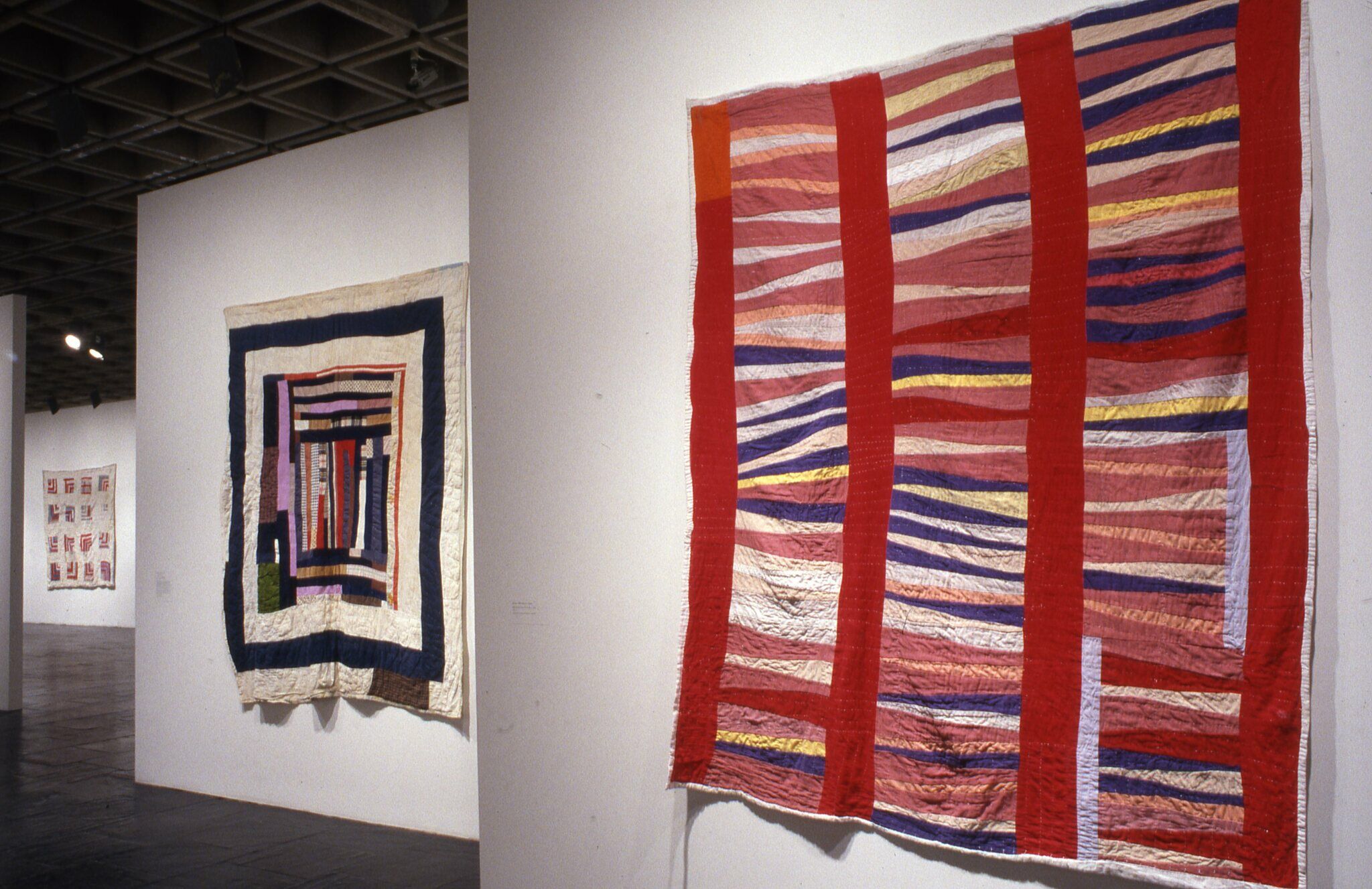 A gallery with colorful quilts displayed on the walls.