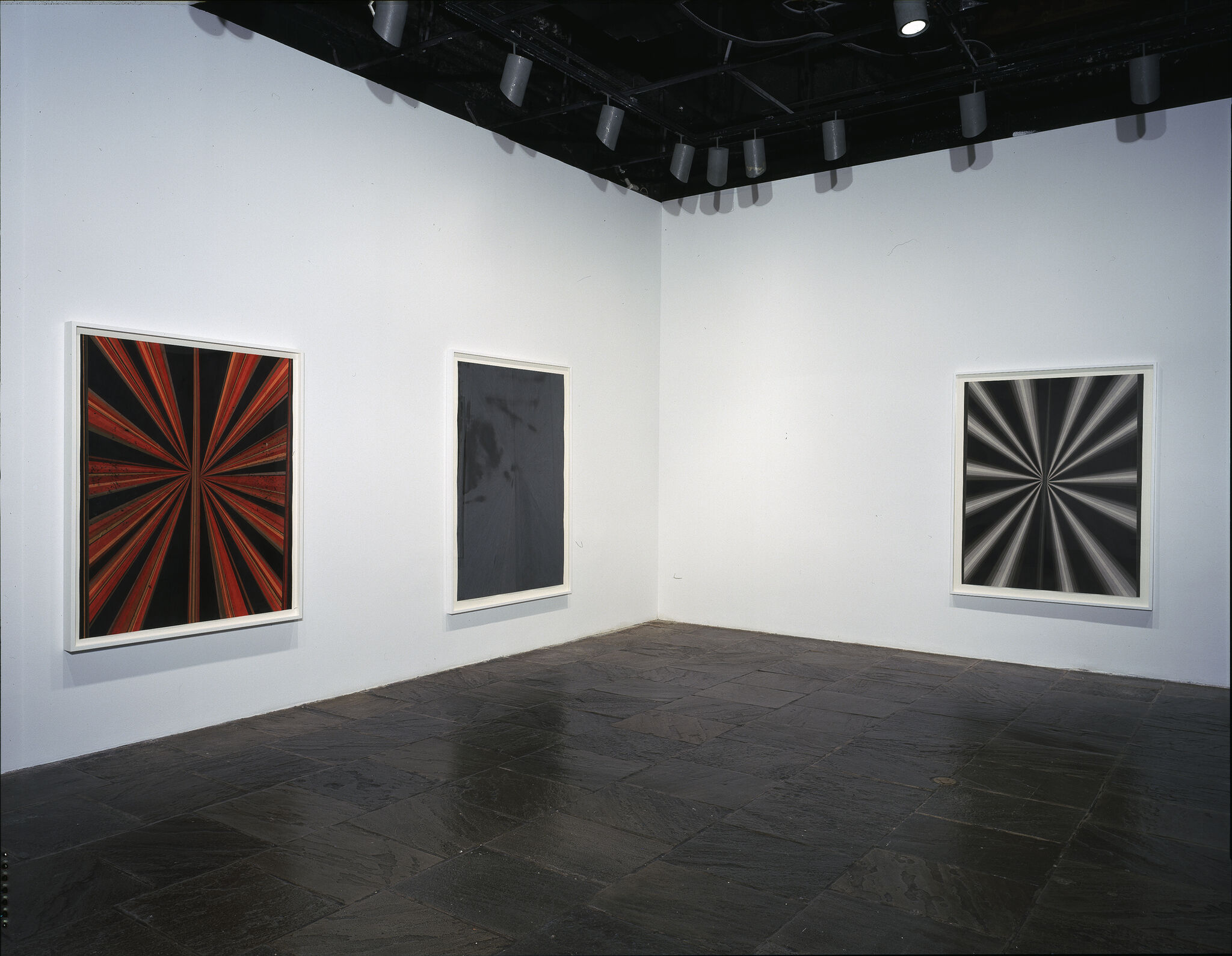 Three abstract paintings displayed in a gallery.