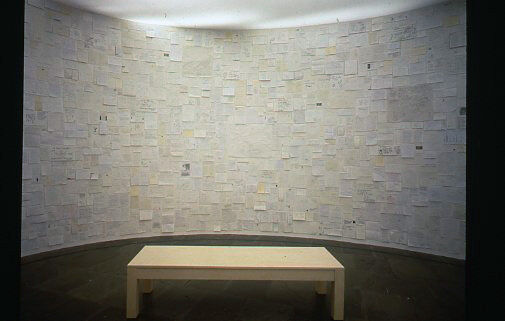 A curved wall covered with small pieces of paper.