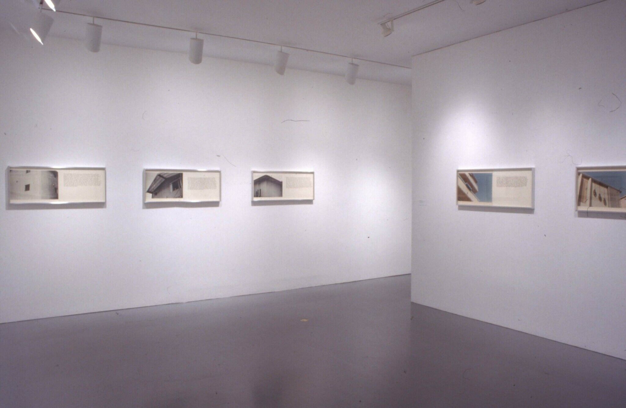 A series of architectural photography displayed alongside text in a gallery.
