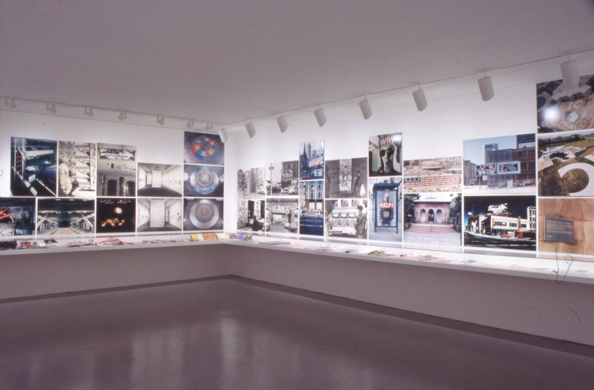 Gallery walls covered in photographs, along with display cases that run along the walls.