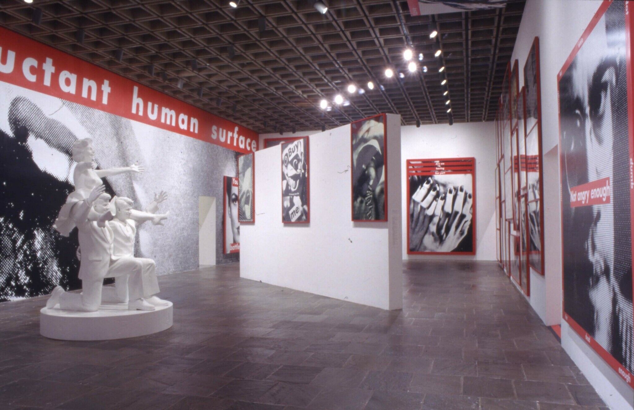A gallery with a white sculpture and works of art composed of black and white photography with red details and text.