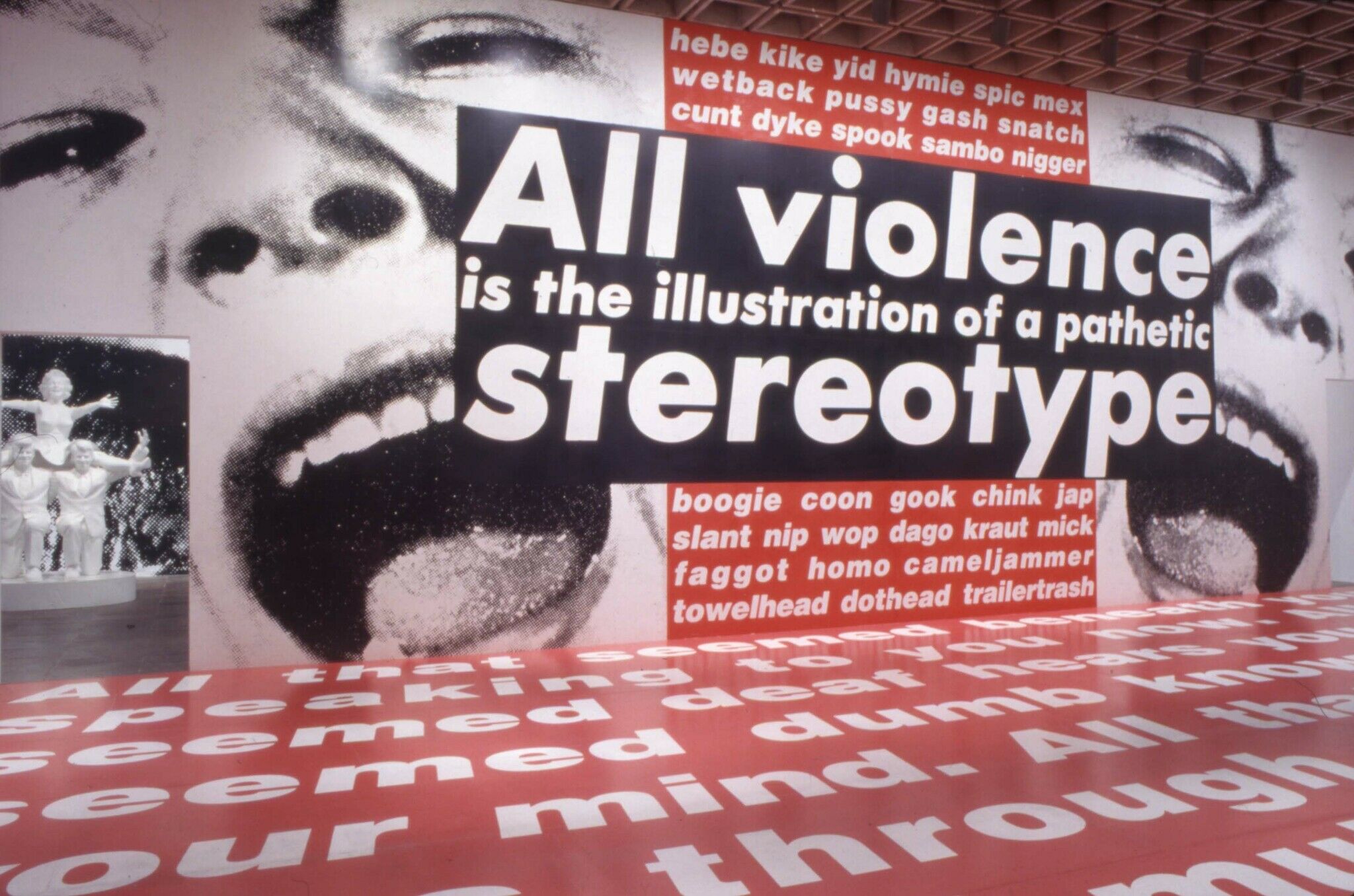 Wall art with black and white photographs of a face with white text highlighted in black that reads, "All violence is the illustration of a pathetic stereotype".