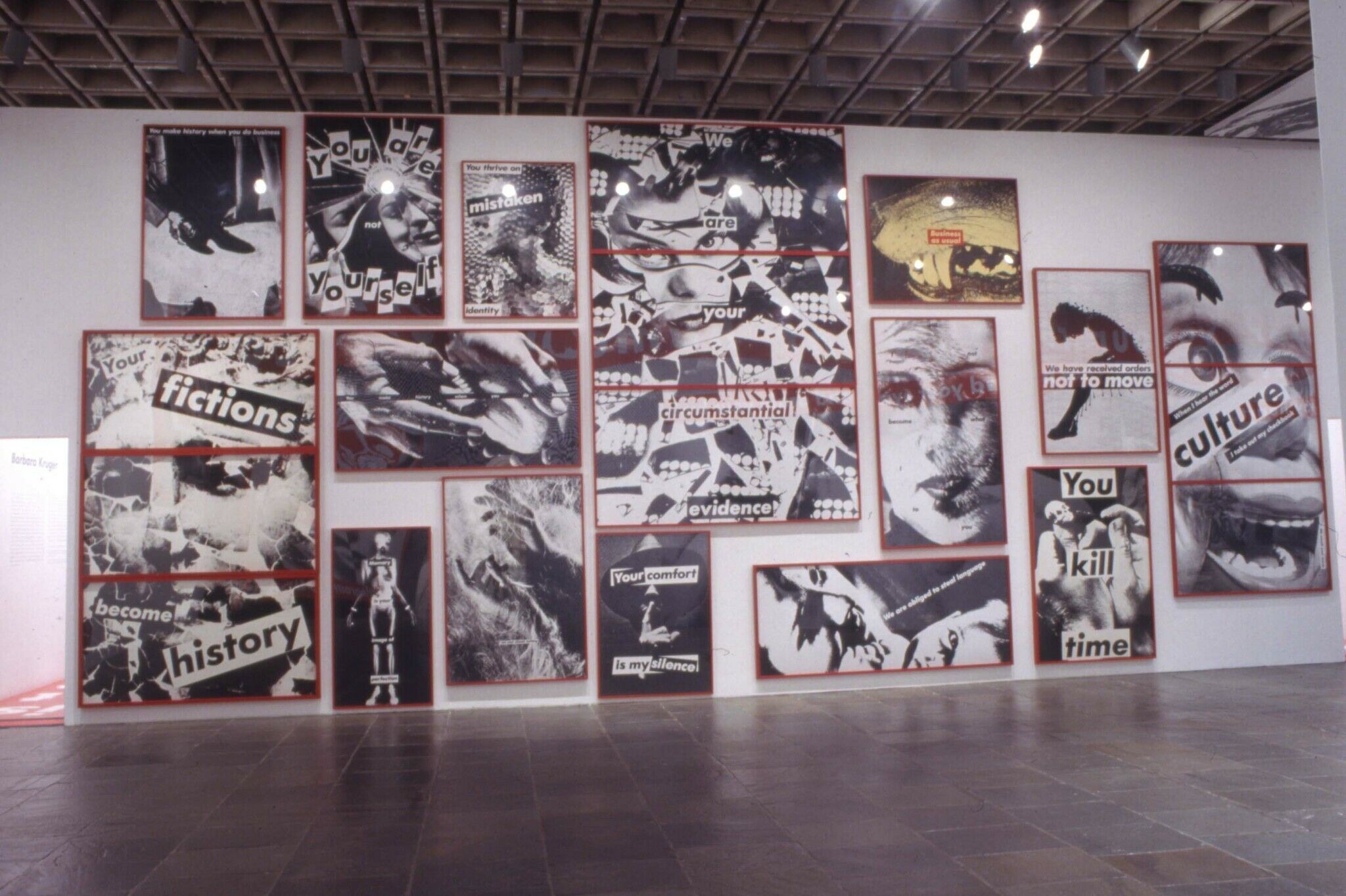 A wall in a gallery filled with black and white photographs with red frames.