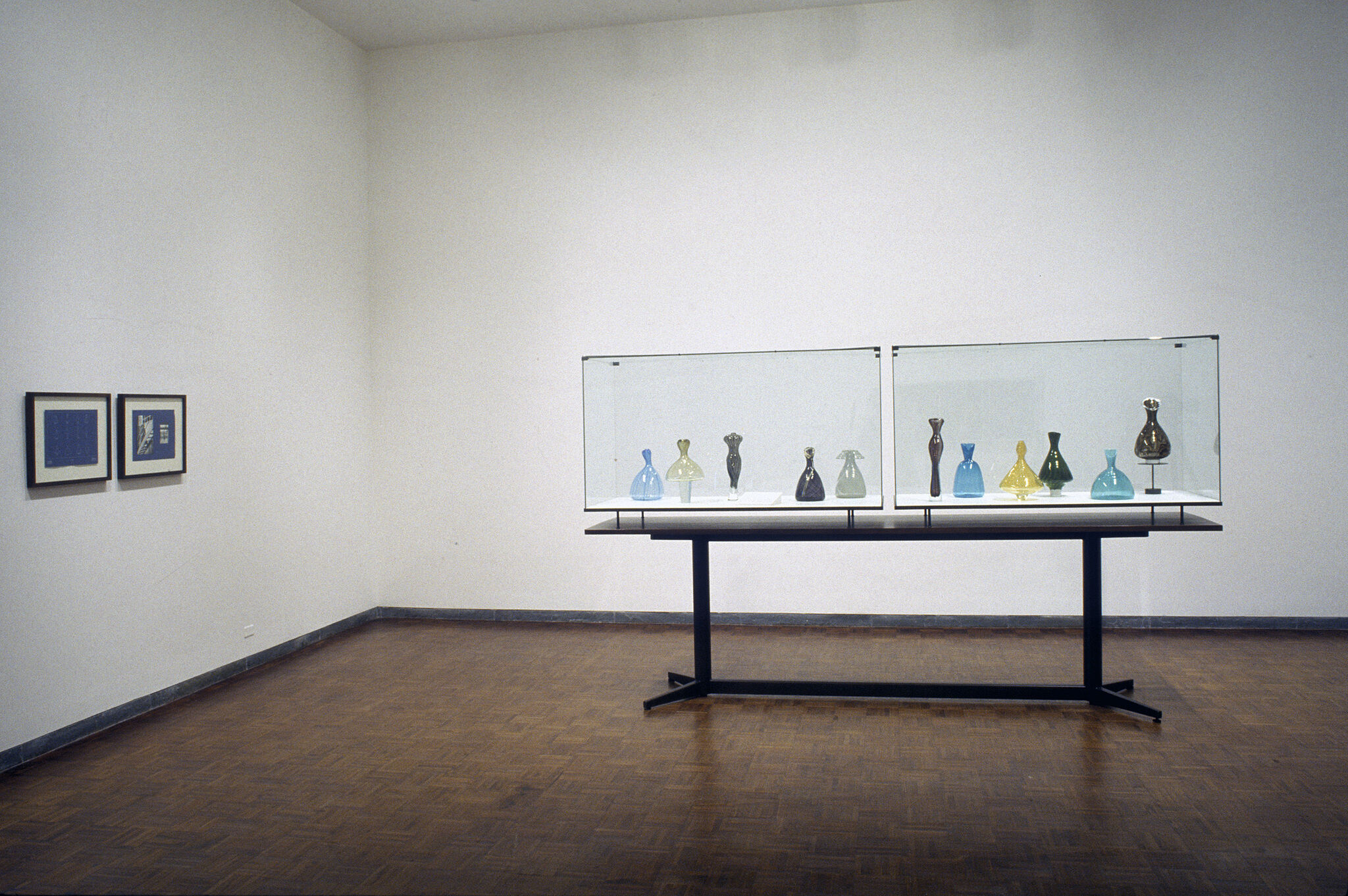 A glass case filled with vases displayed in a gallery.
