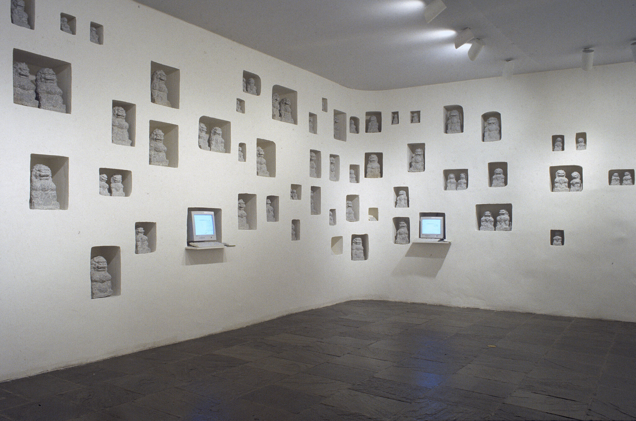 A gallery with sculptures and two small monitors displayed inside the walls.