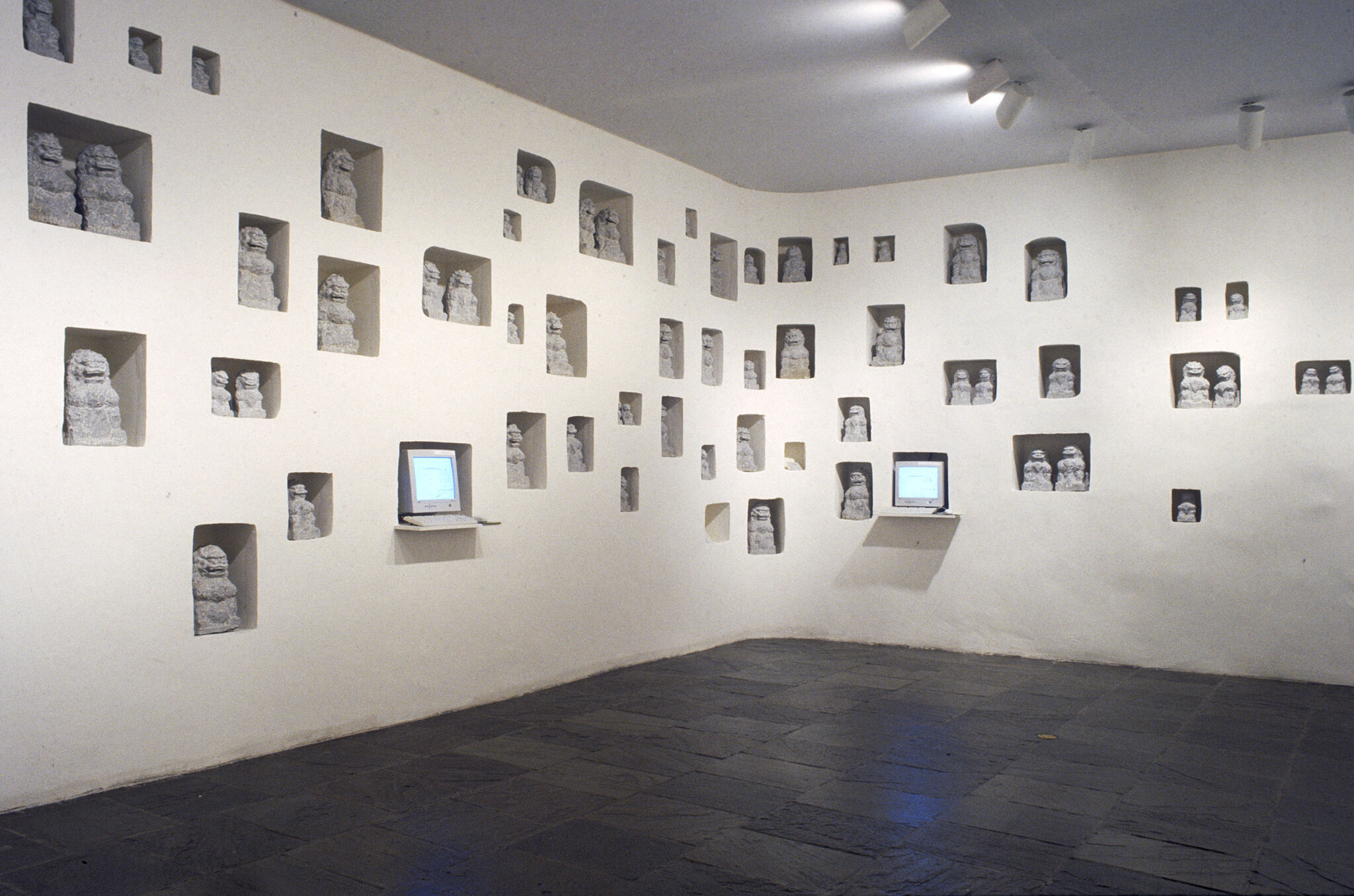 A gallery with sculptures and two small monitors displayed inside the walls.