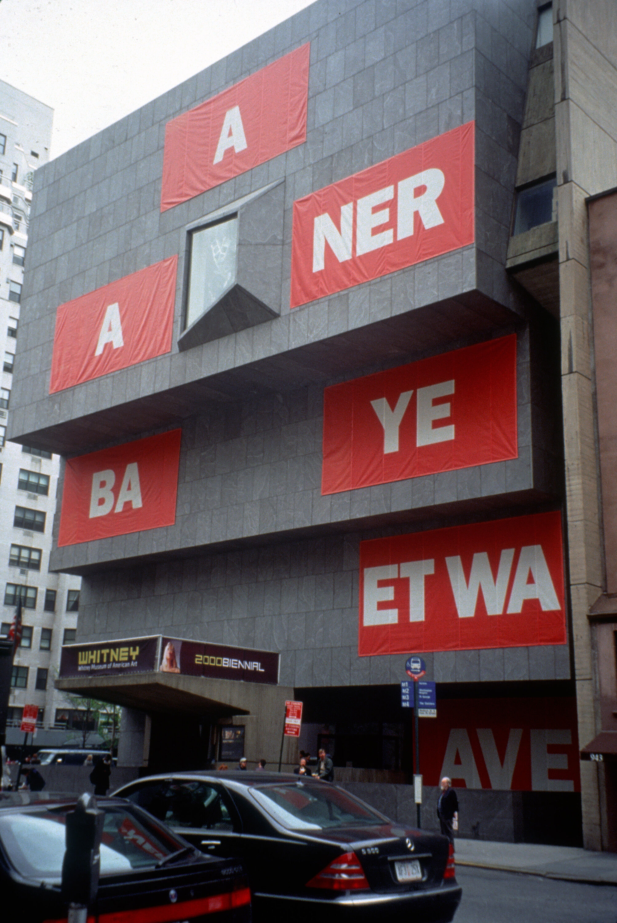The outside of a building with red banners that have white text on them.