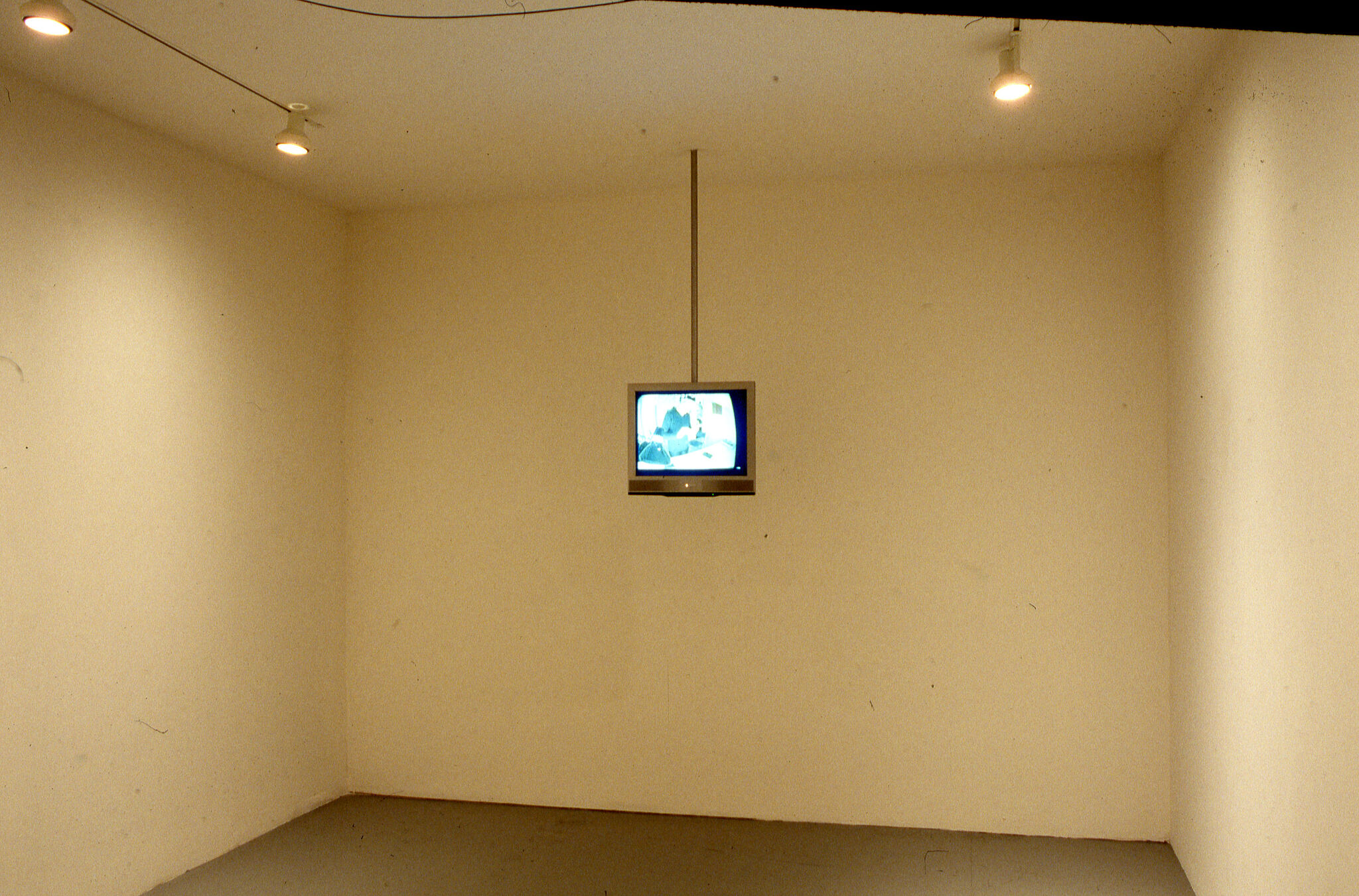 A television set hanging from the ceiling in a gallery.