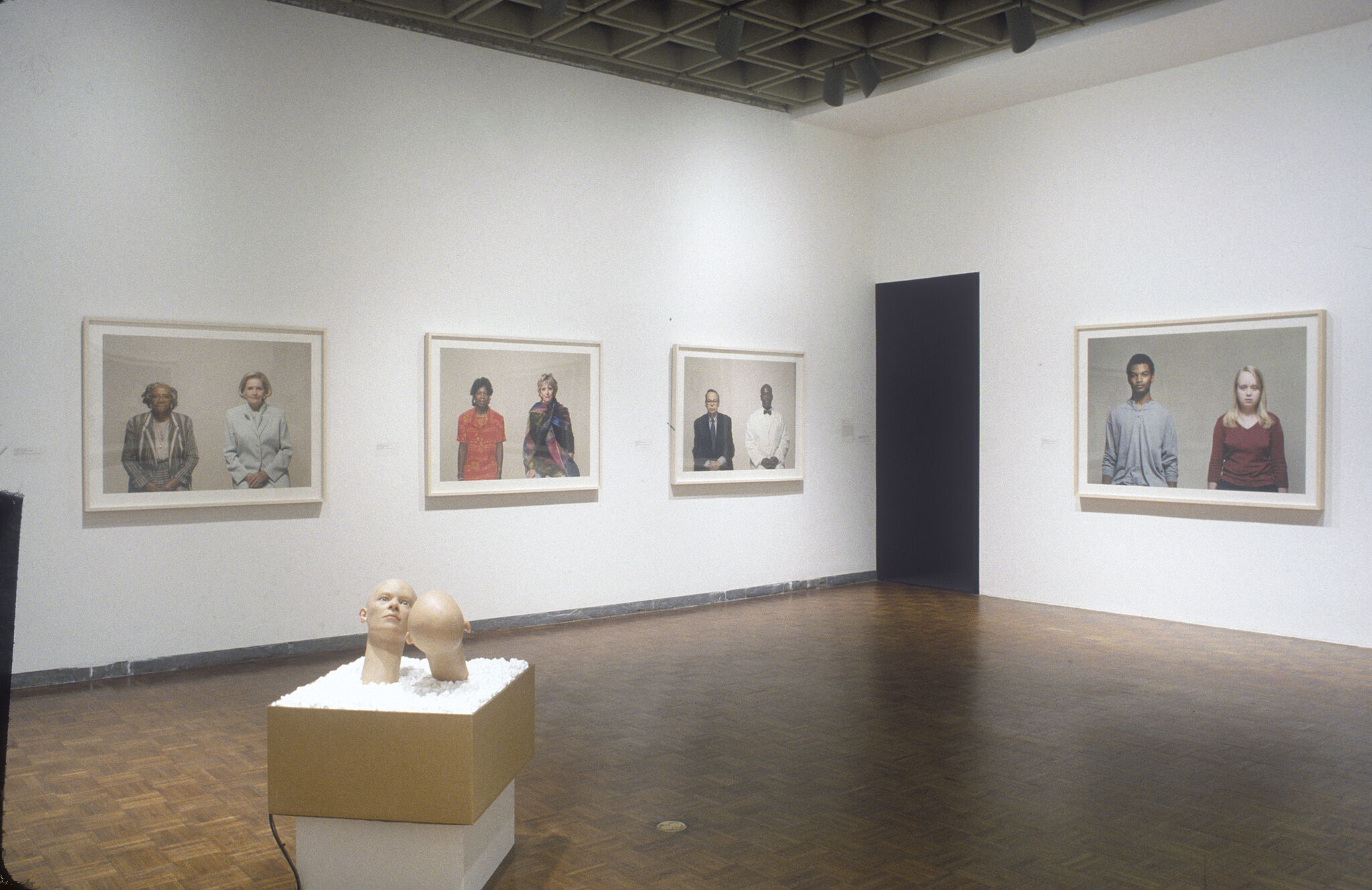 A gallery with portraits of people displayed on the walls and a sculpture.