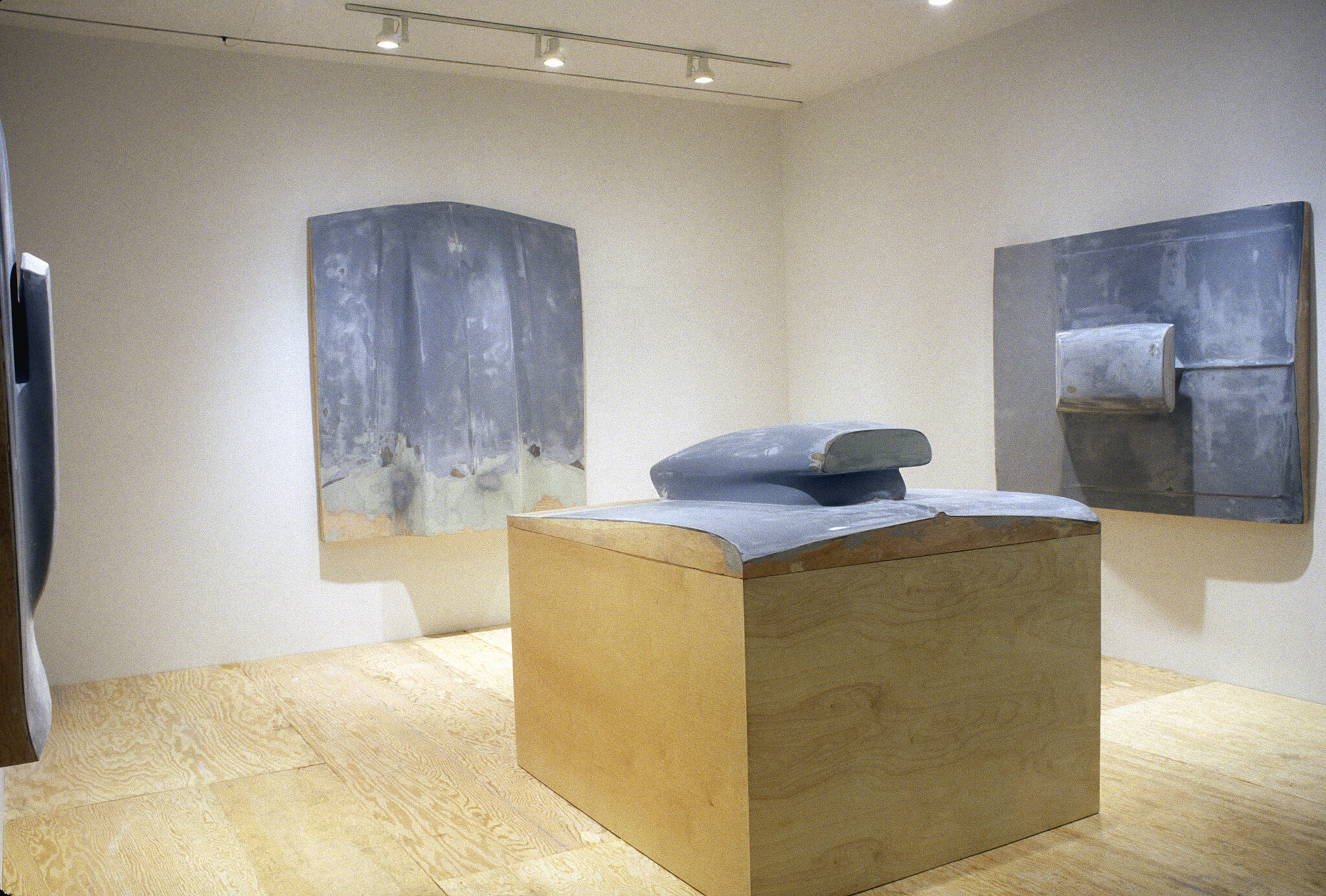 A gallery with blue sculptures on the walls and on the floor.