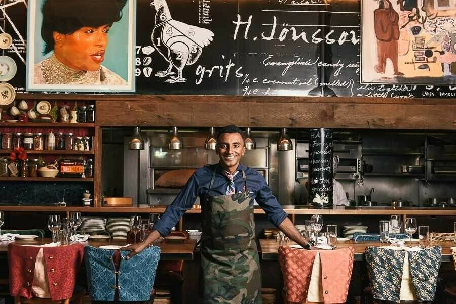 Marcus Samuelsson stands in front of a bar. 