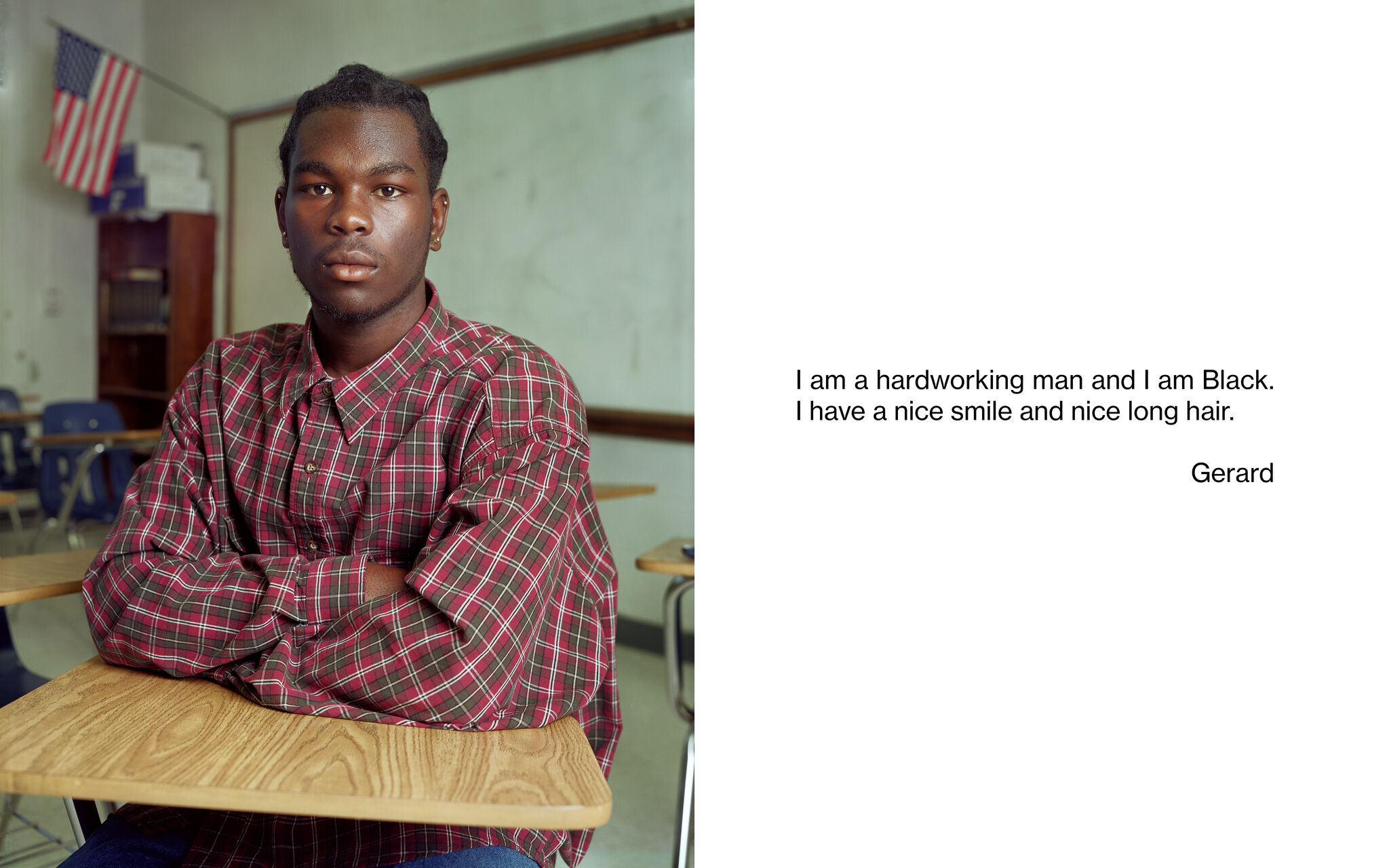 A portrait of a student resting their arms on a school desk and facing the camera. "I am a hardworking man and I am Black. I have a nice smile and nice long hair. Gerard"