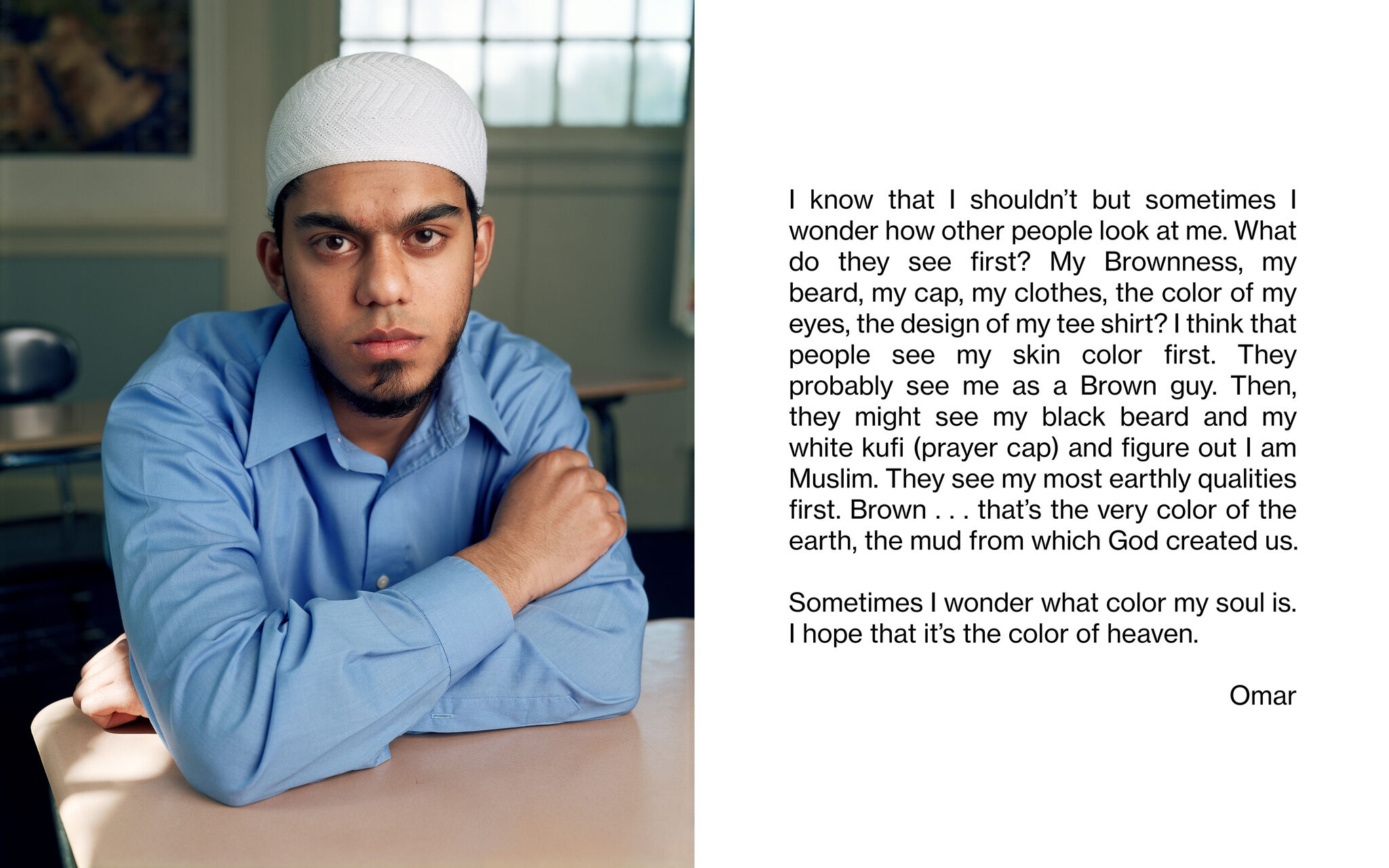 A portrait of a student resting their arms on a school desk and facing the camera. "I know that I shouldn't but sometimes I wonder how other people look at me. What do they see first? My Brownness, my beard, my cap, my clothes, the color of my eyes, the design of my tee shirt? I think that people see my skin color first. They probably see me as a Brown guy. Then, they might see my black beard and my white kufi (prayer cap) and figure out that I am Muslim. They see my most earthly qualities first. Brown . . . that's the very color of the earth, the mud from which God created us. Sometime I wonder what color my soul is. I hope that it's the color of heaven. Omar"