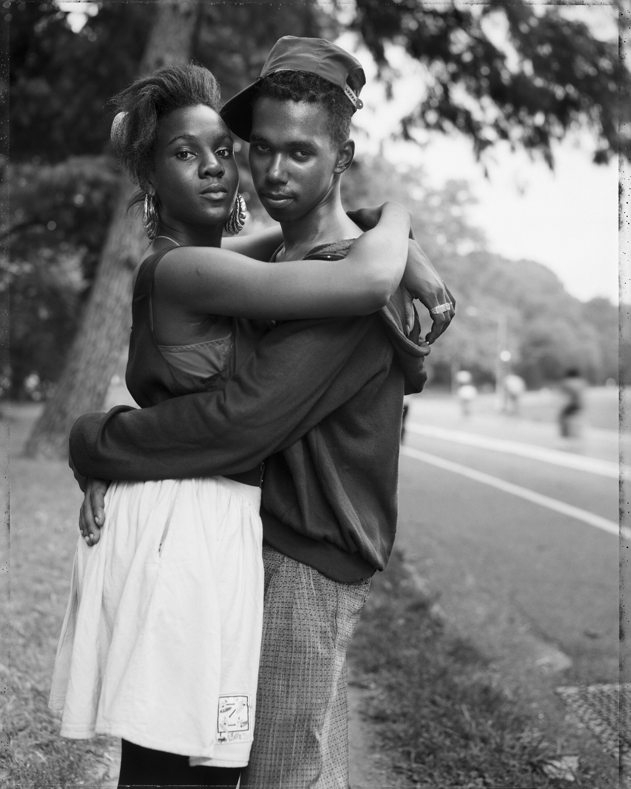 A portrait of a young couple embracing on the side of the road. 