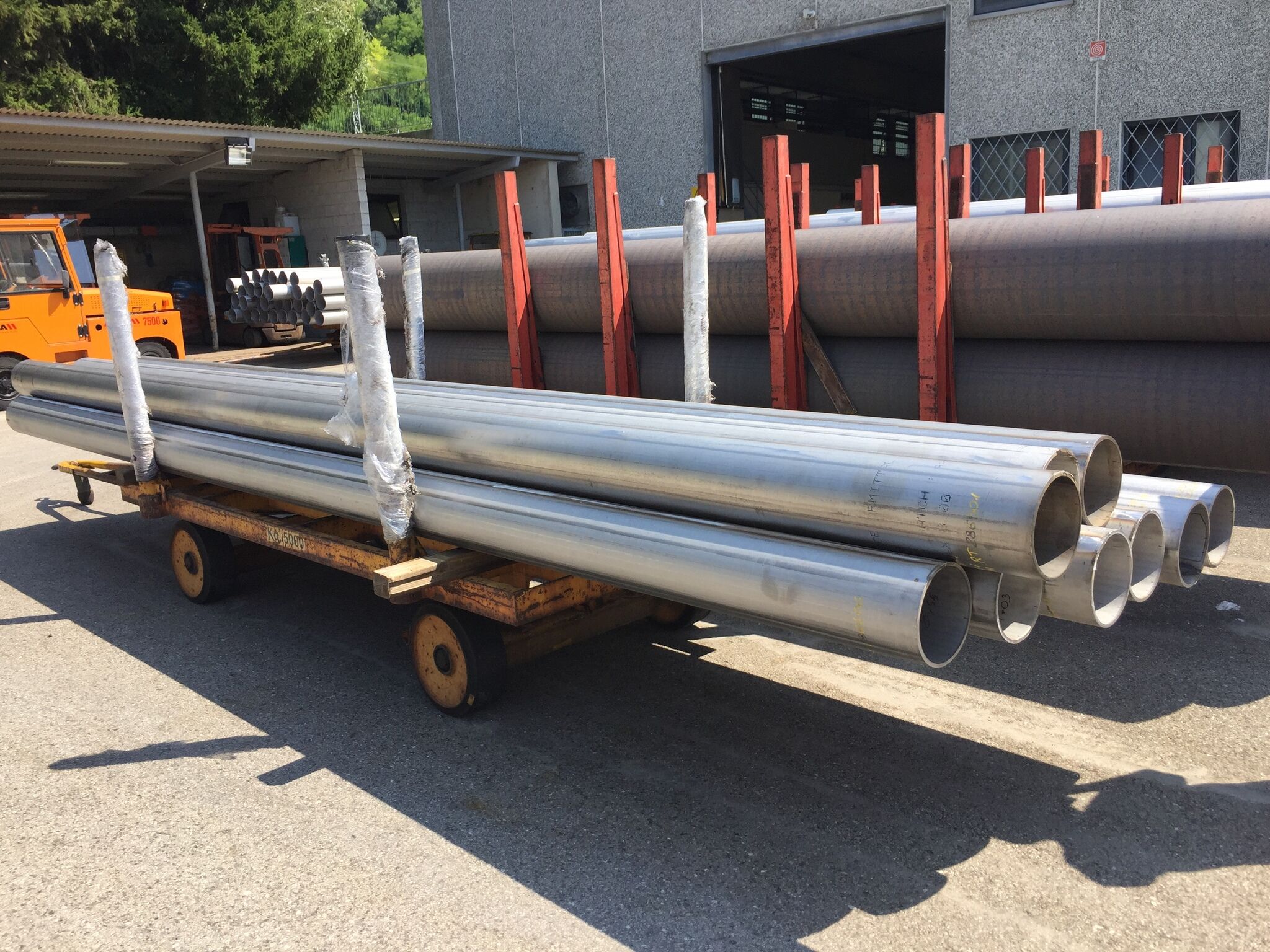 Large steel pipes stacked on a rolling cart.