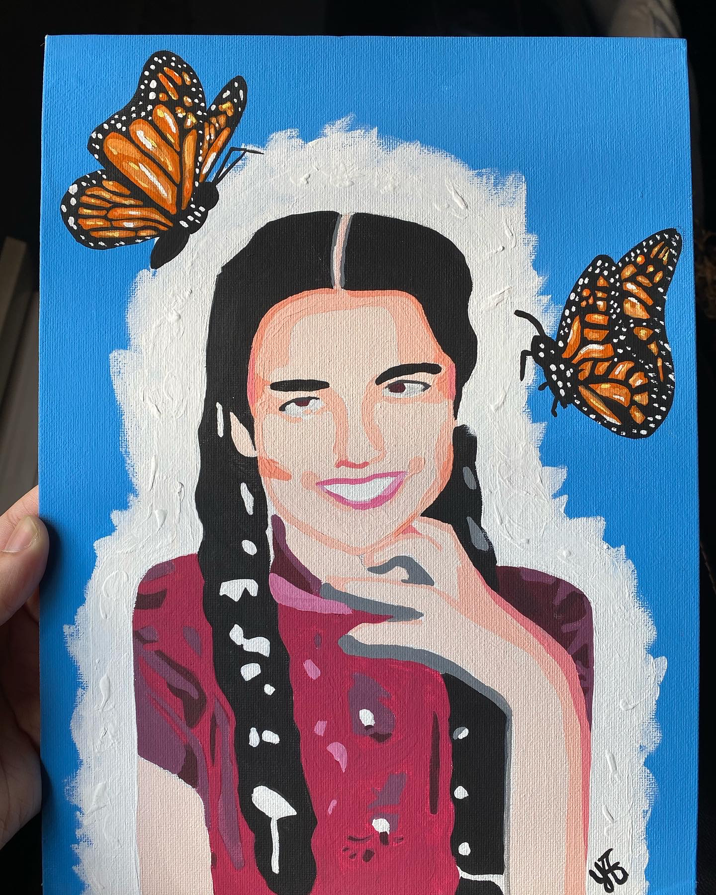 A portrait of Teresa-Maria Mirabal against a blue background filled with butterflies. 
